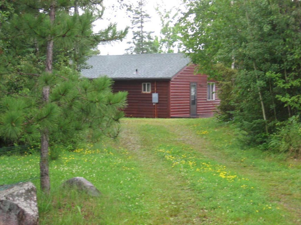 Image 3: View of side of home with faux log siding, roof with shingles, and a yard, Side Of Structure