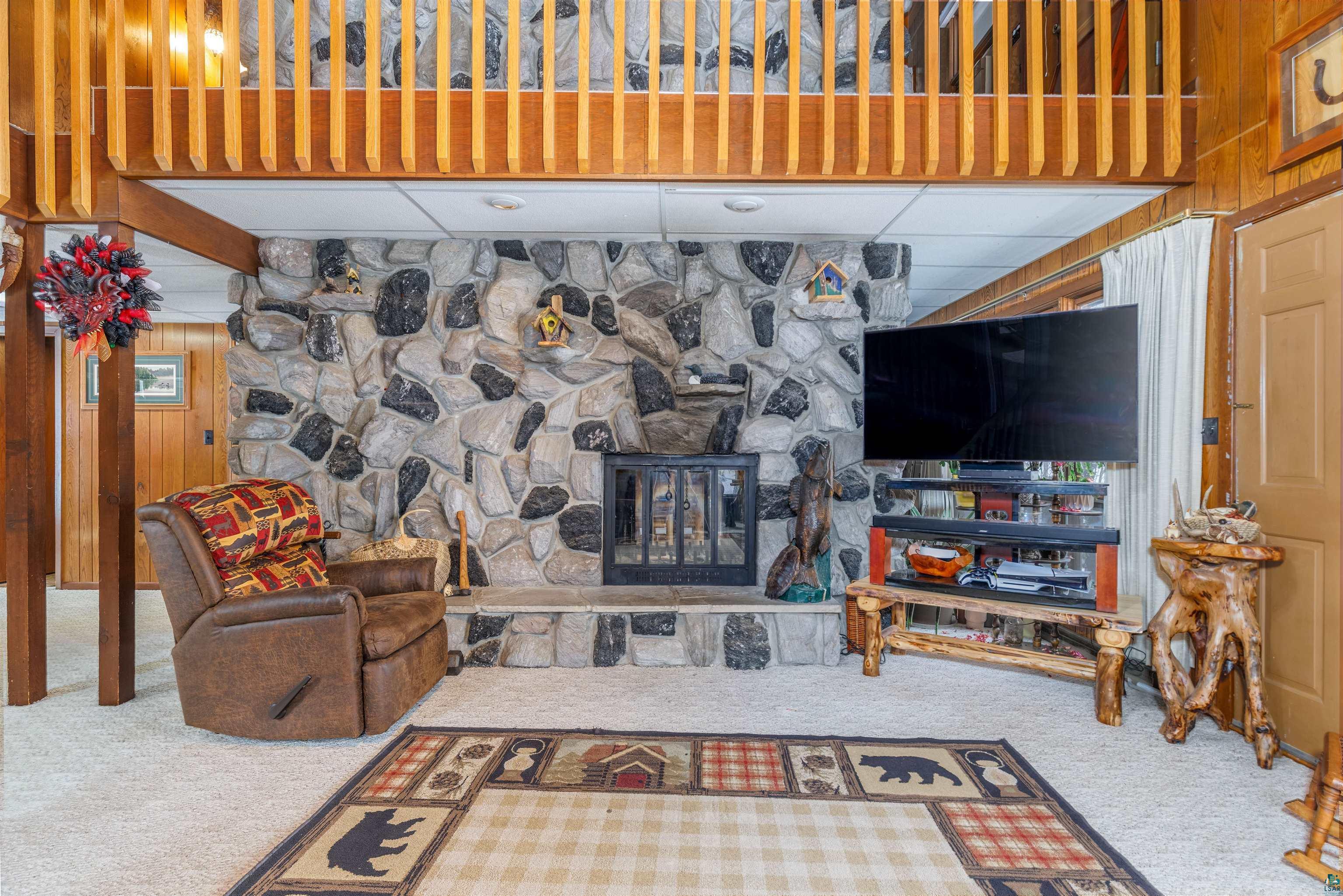 Image 2: Carpeted living room with a drop ceiling, a stone fireplace, and wooden walls, Living Room