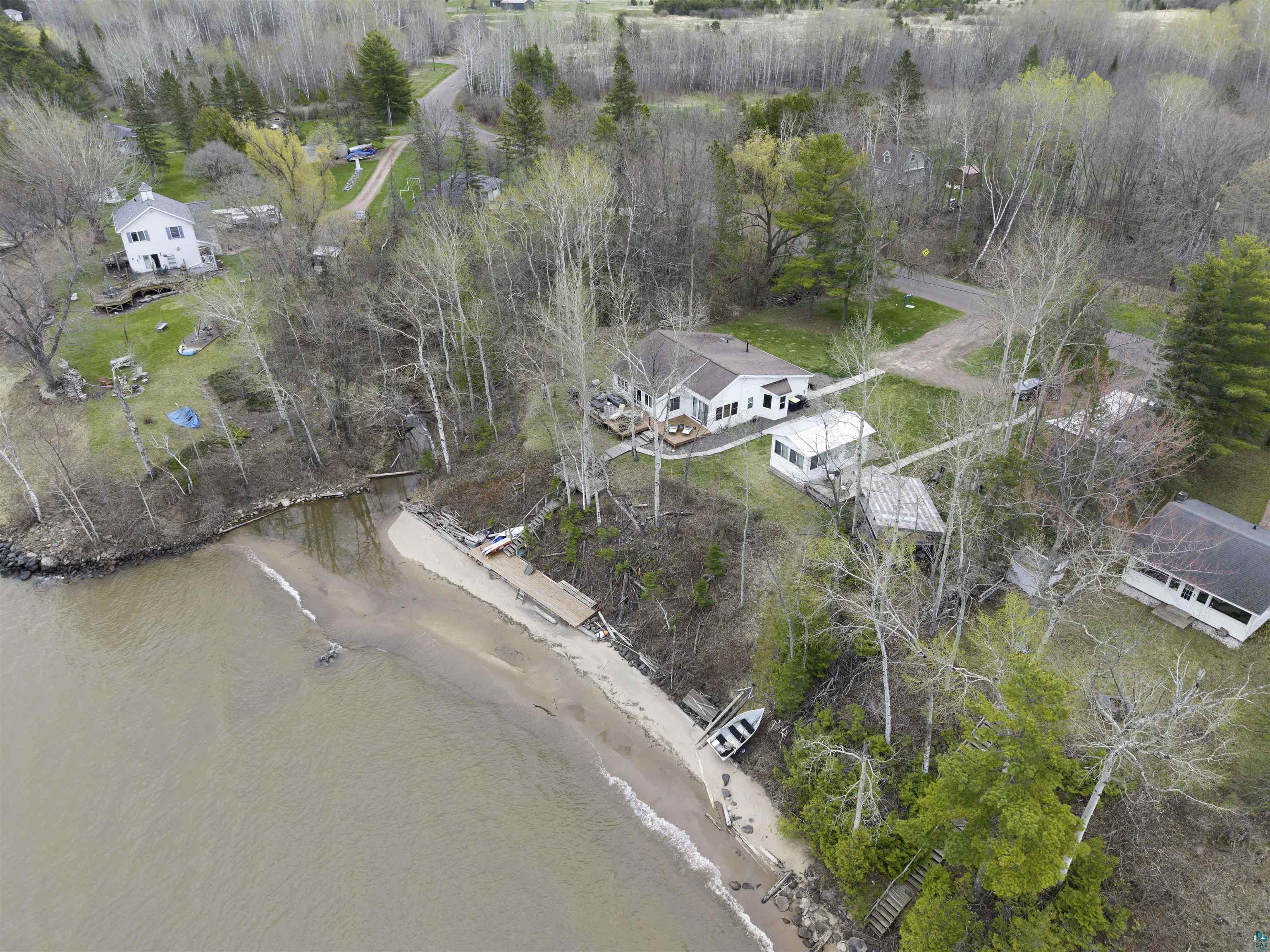 Image 2: Expansive waterfront property featuring a sandy beach, a private dock, and multiple mature trees, Aerial View