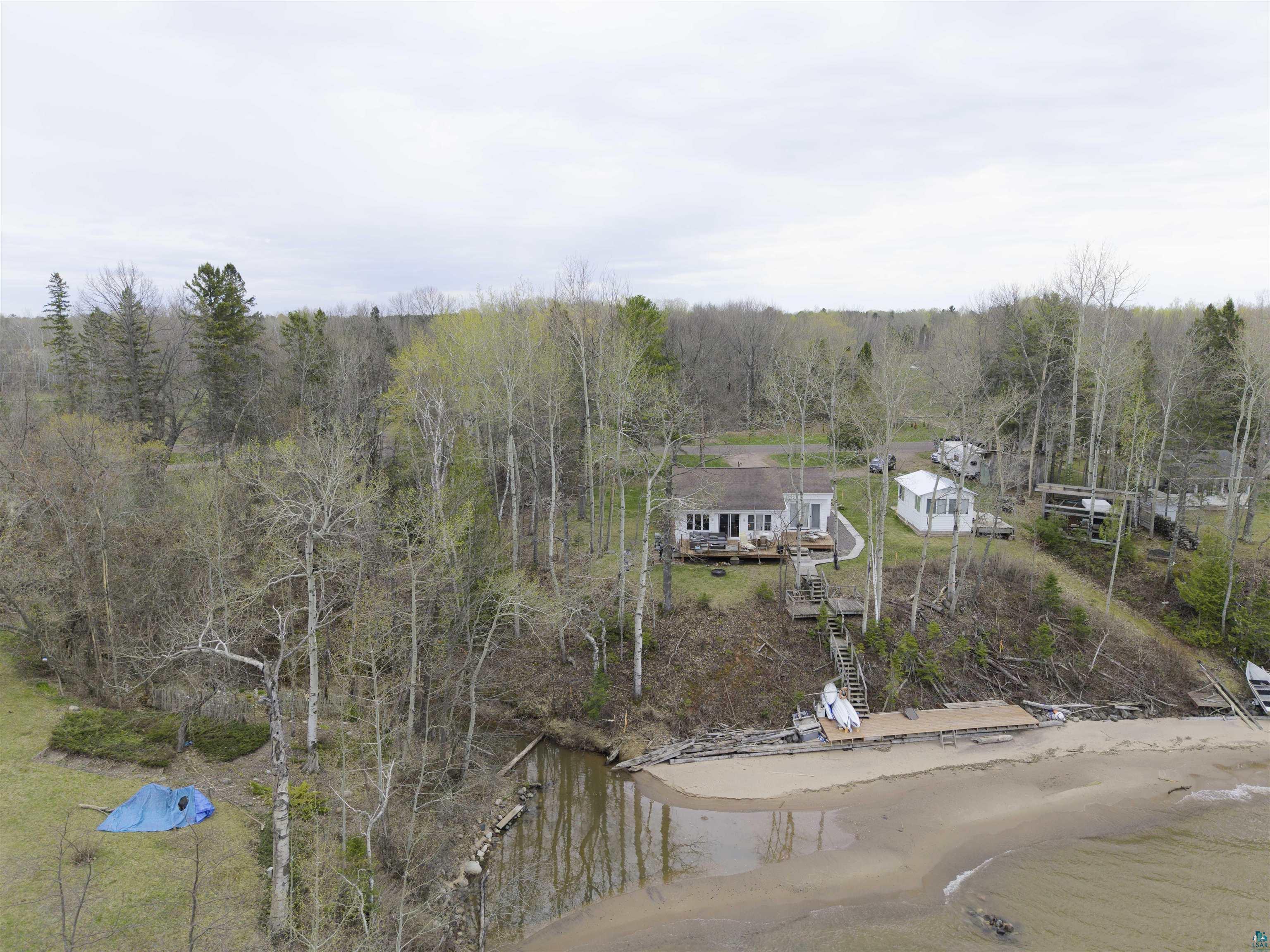 Image 3: Waterfront property featuring a sandy beach, private dock, and wooded surroundings, Aerial View