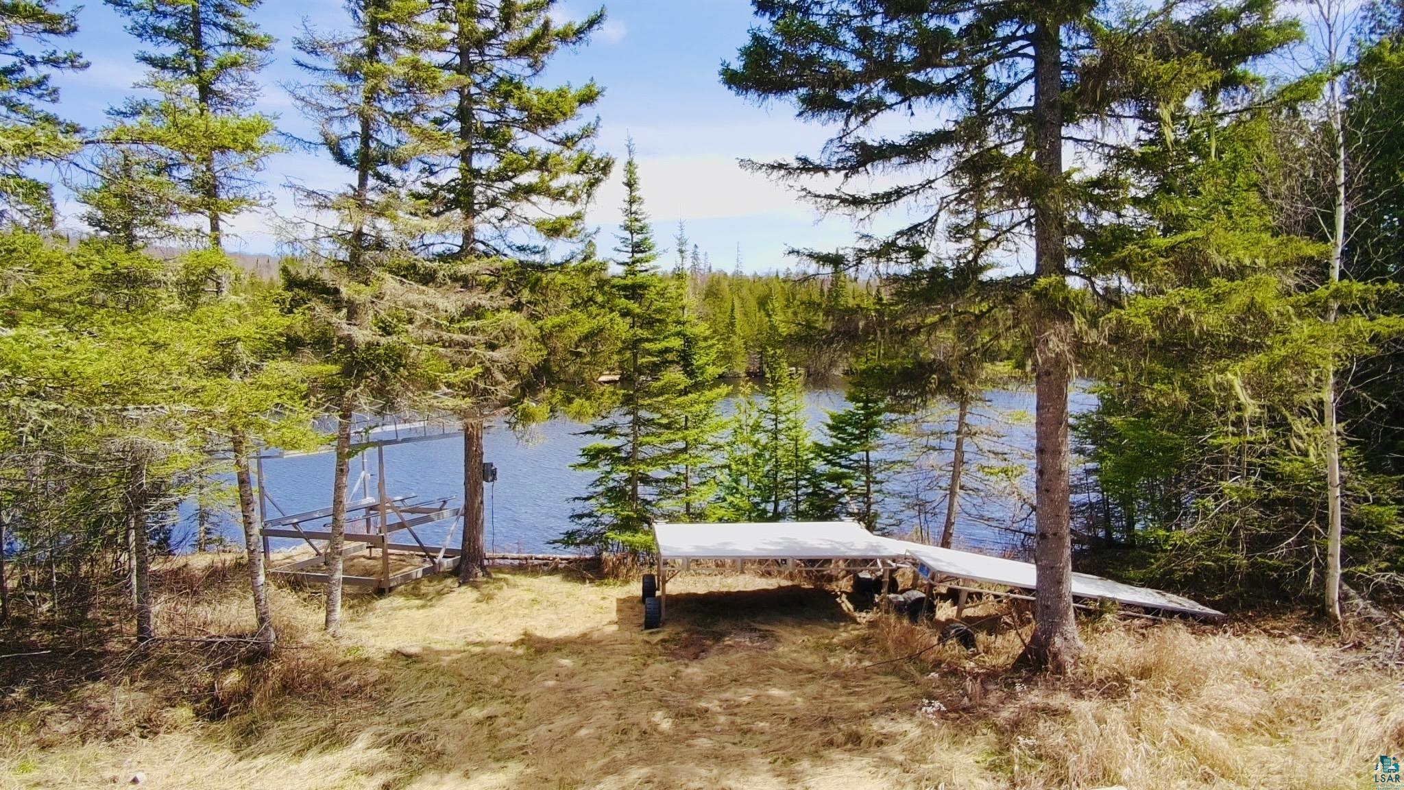 Image 2: Waterfront property featuring a private boat lift, a dock structure, and mature evergreen trees, View