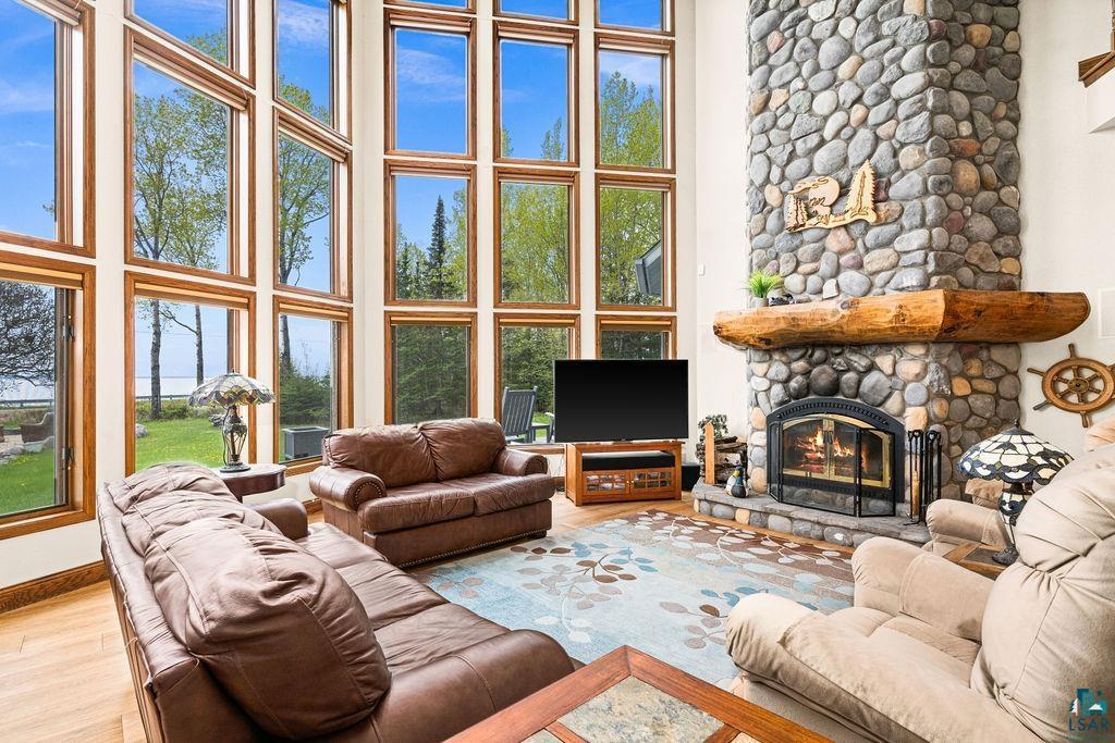 Image 1: Living area featuring a high ceiling, a stone fireplace, wood finished floors, and baseboards, Living Room