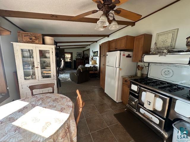 Image 2: Kitchen with brown cabinets, beamed ceiling, freestanding refrigerator, exhaust hood, and a textured ceiling, Kitchen