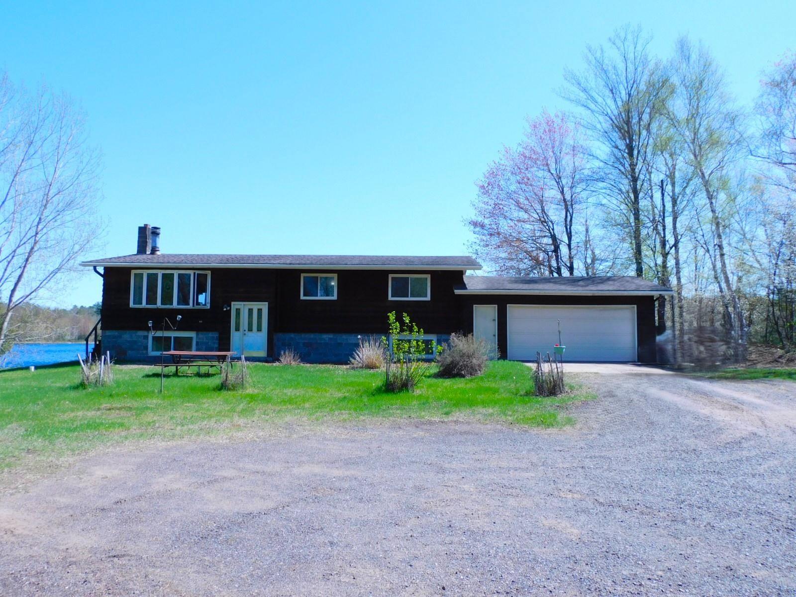 Image 3: View of front of home featuring a chimney, dirt driveway, and a garage, Front Of Structure