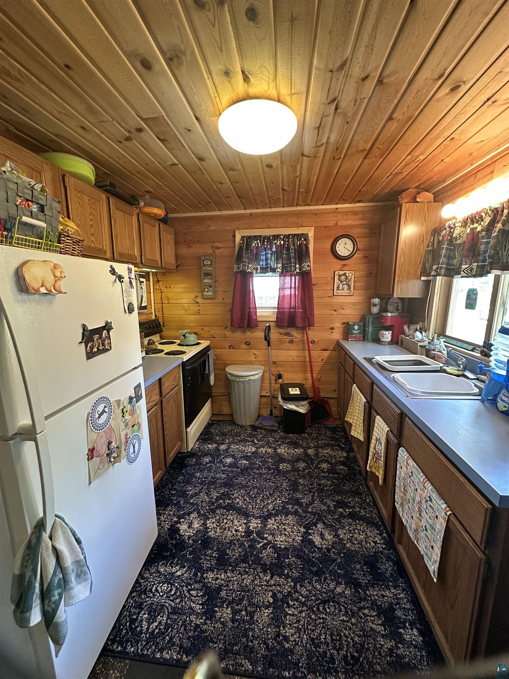 Image 2: Kitchen with white appliances, wood ceiling, brown cabinets, a sink, and wooden walls, Kitchen