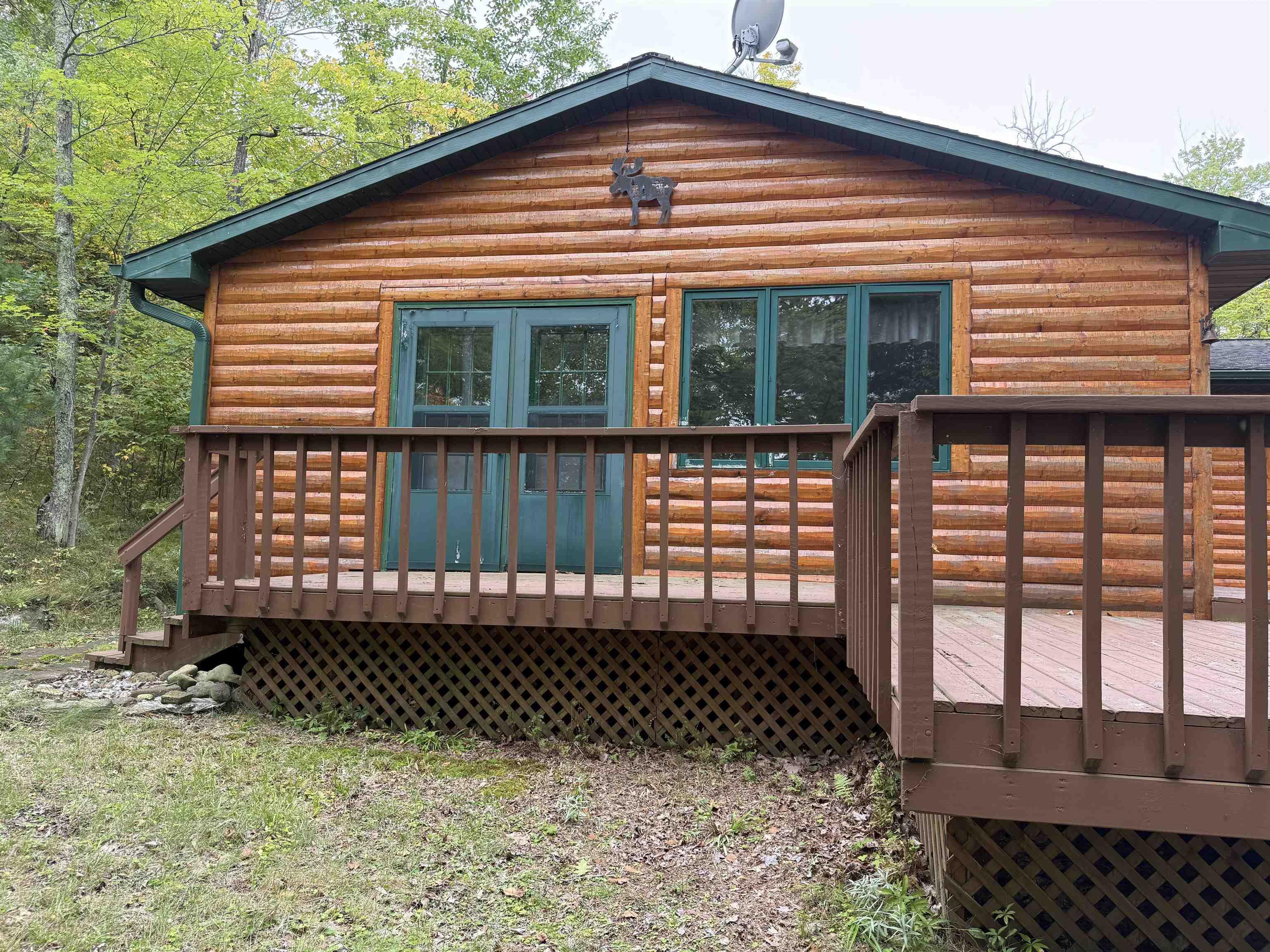 Image 1: Rear view of house featuring a deck and log veneer siding, Back Of Structure