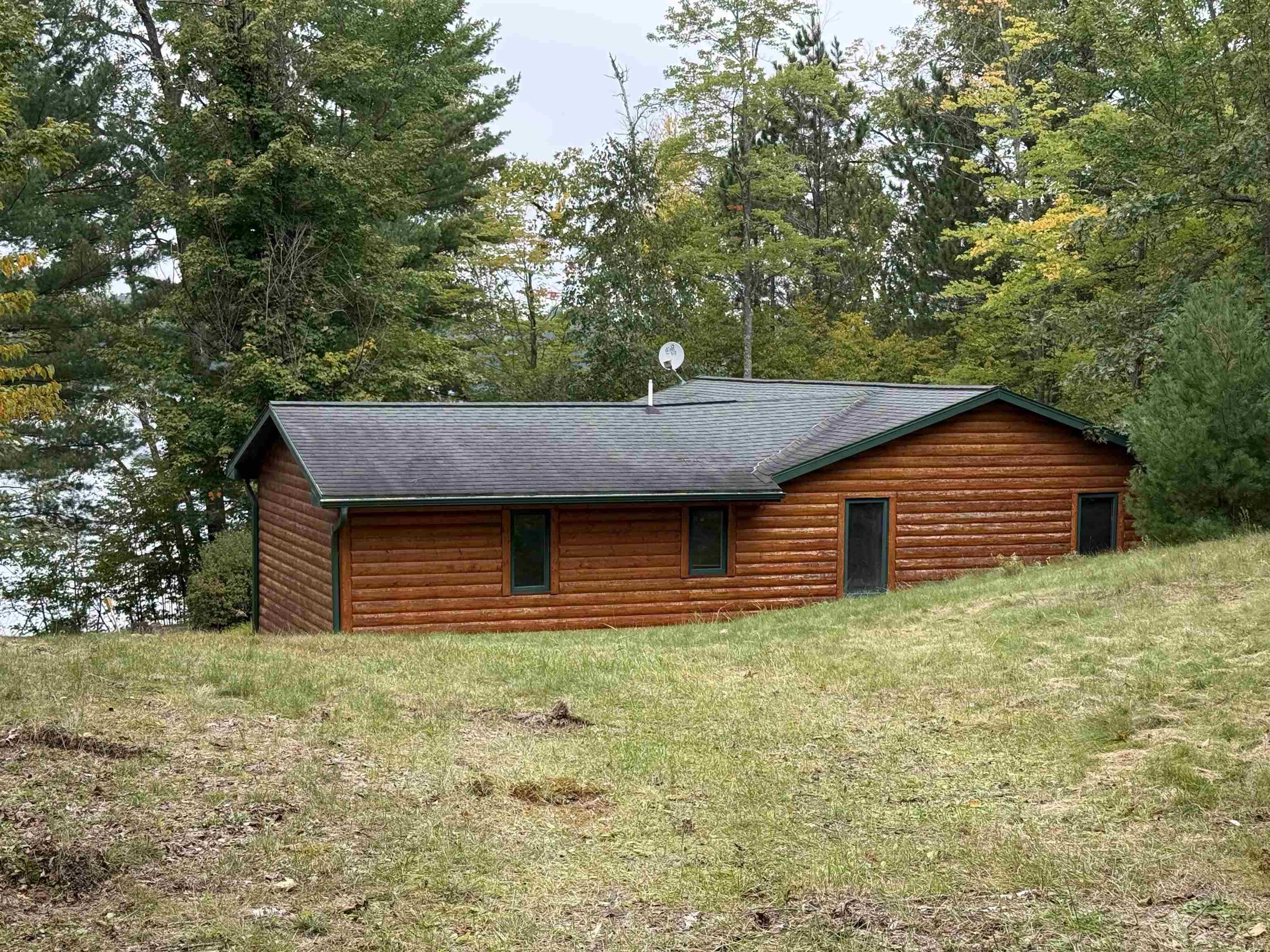 Image 2: View of side of property featuring log veneer siding and roof with shingles, Side Of Structure