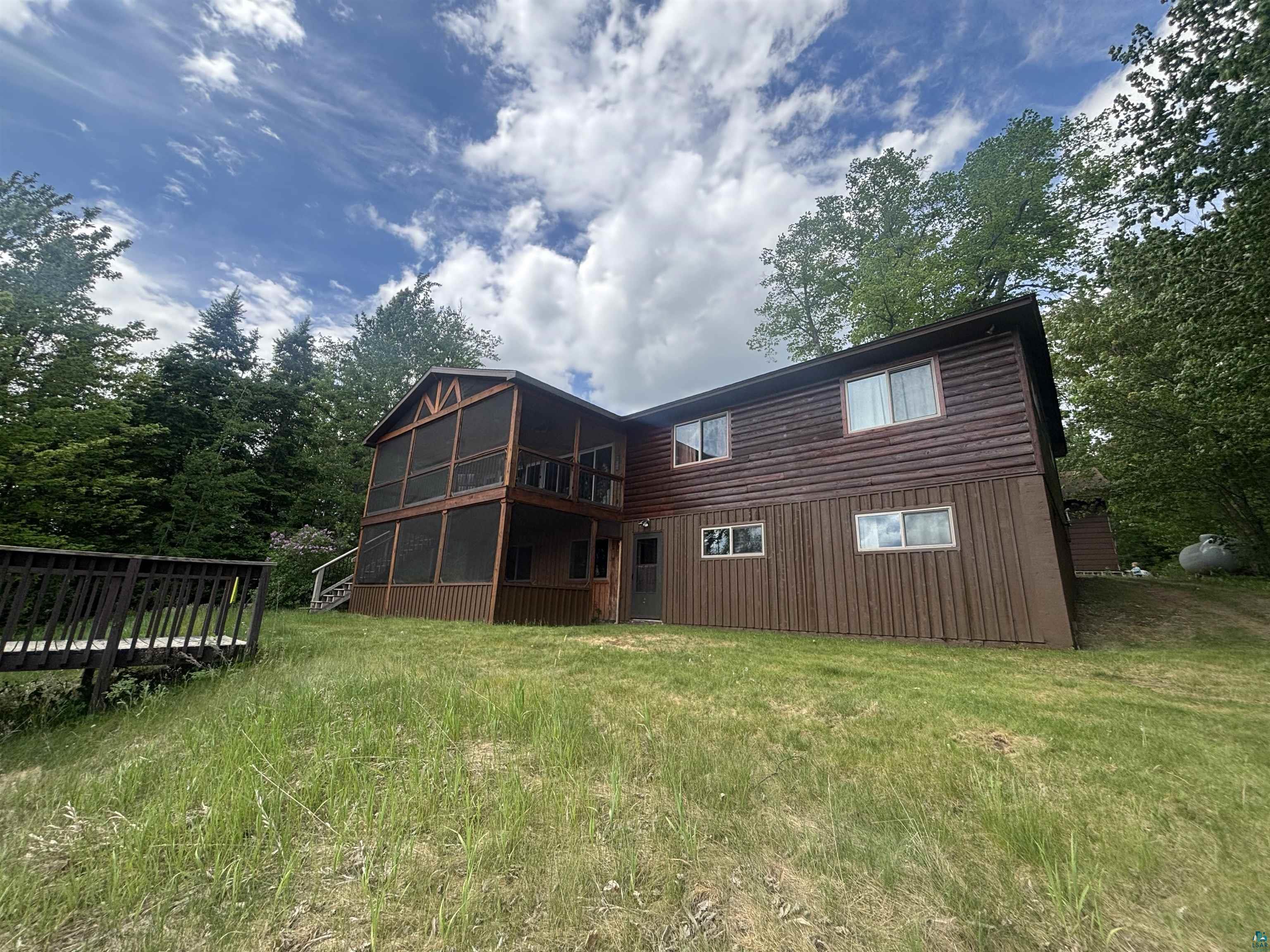 Image 1: Two-story home with wood siding and an elevated screened-in porch, Back Of Structure