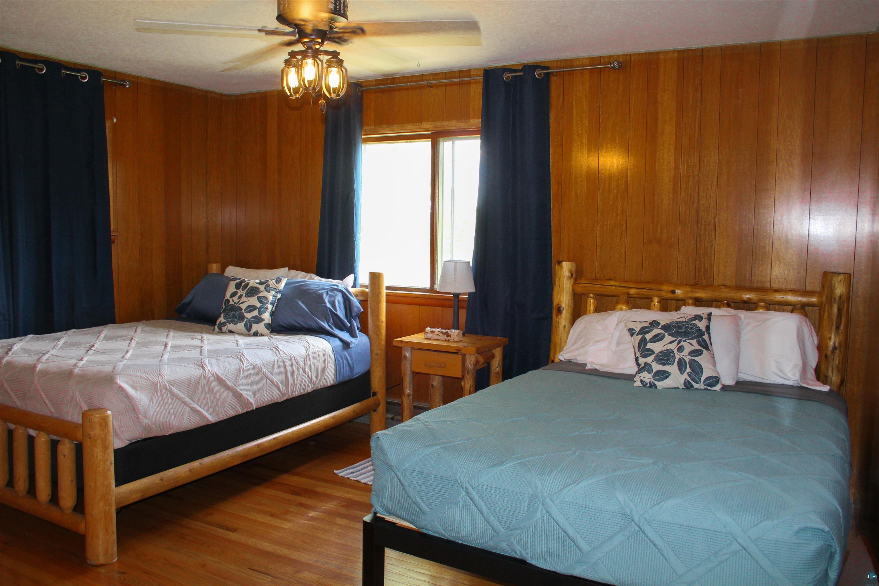 Image 3: Bedroom with wood walls, a ceiling fan, and wood finished floors, Bedroom