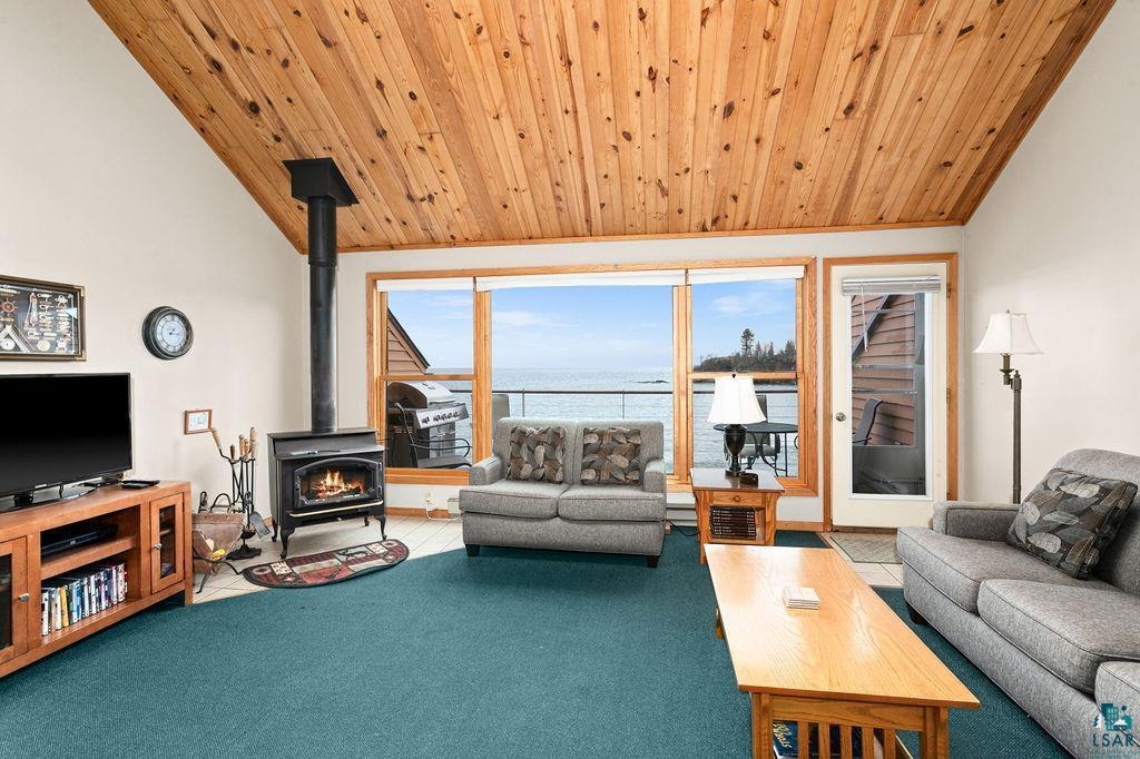 Image 1: Carpeted living room featuring wooden ceiling, a water view, a wood stove, and lofted ceiling, Living Room