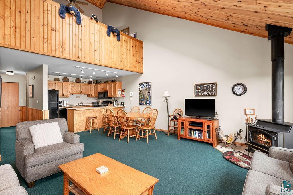 Image 2: Carpeted living room with wood ceiling, track lighting, high vaulted ceiling, and a wood stove, Living Room