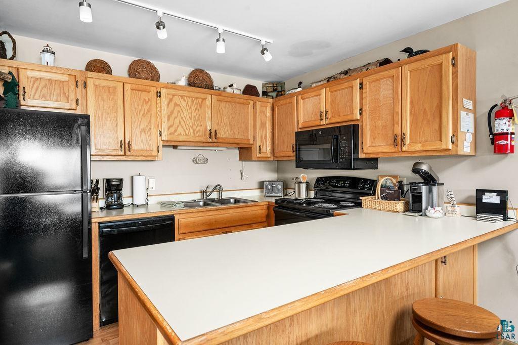 Image 3: Kitchen featuring sink, black appliances, kitchen peninsula, and a kitchen bar, Kitchen