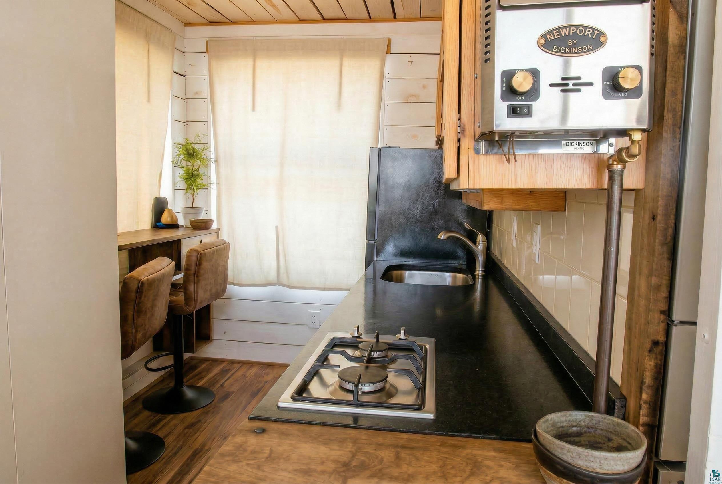 Image 2: Kitchen featuring stainless steel gas stovetop, water heater, freestanding refrigerator, dark wood-style floors, and wood ceiling, Kitchen