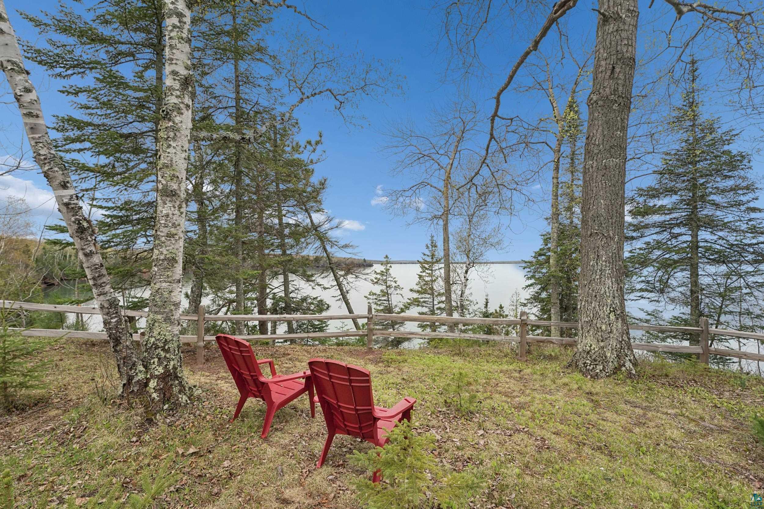 Image 2: Natural landscape featuring mature trees and a rustic wood fence, Yard
