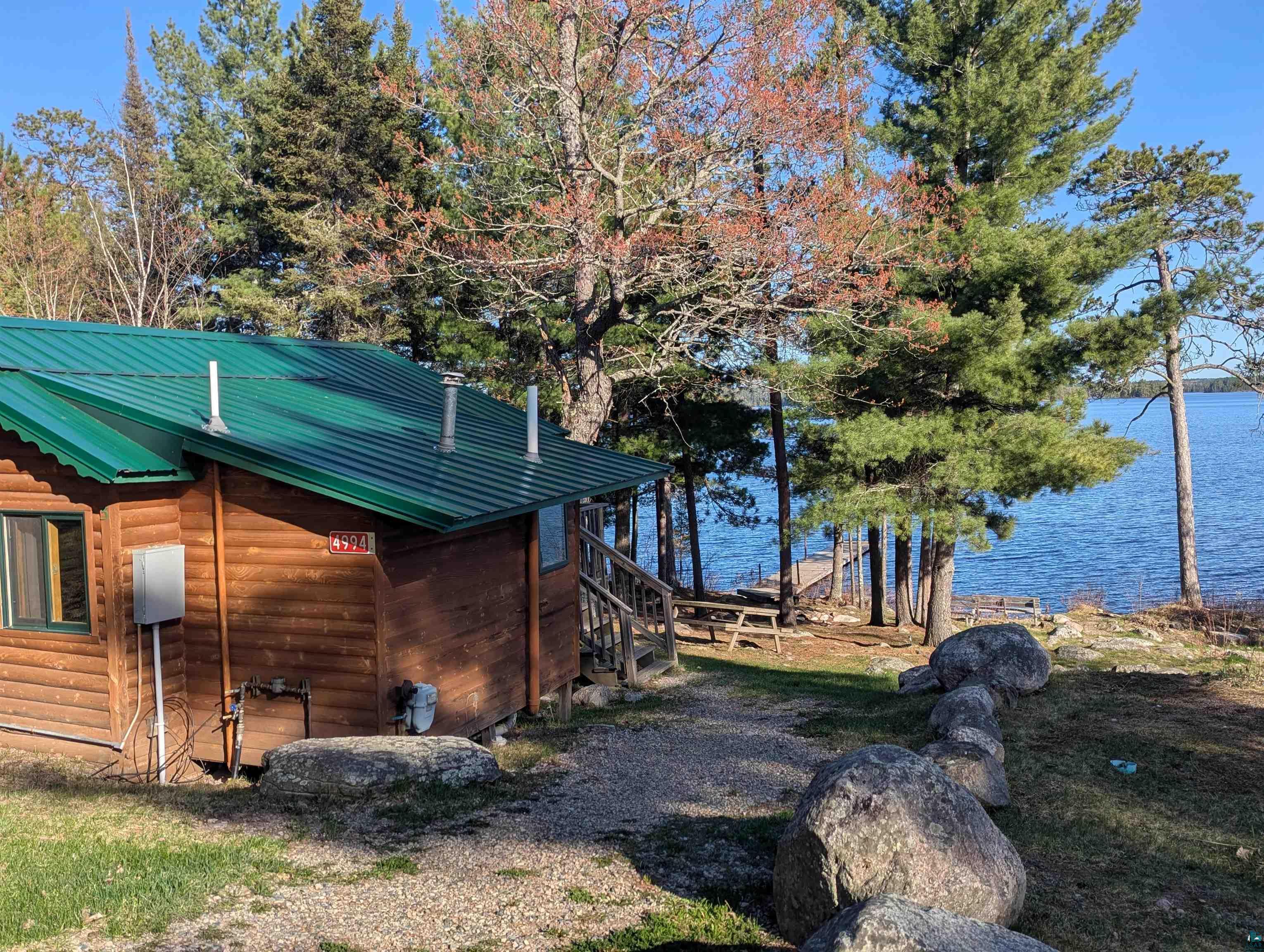 Image 0: View of property exterior with a water view, metal roof, and log veneer siding, Side of cabin