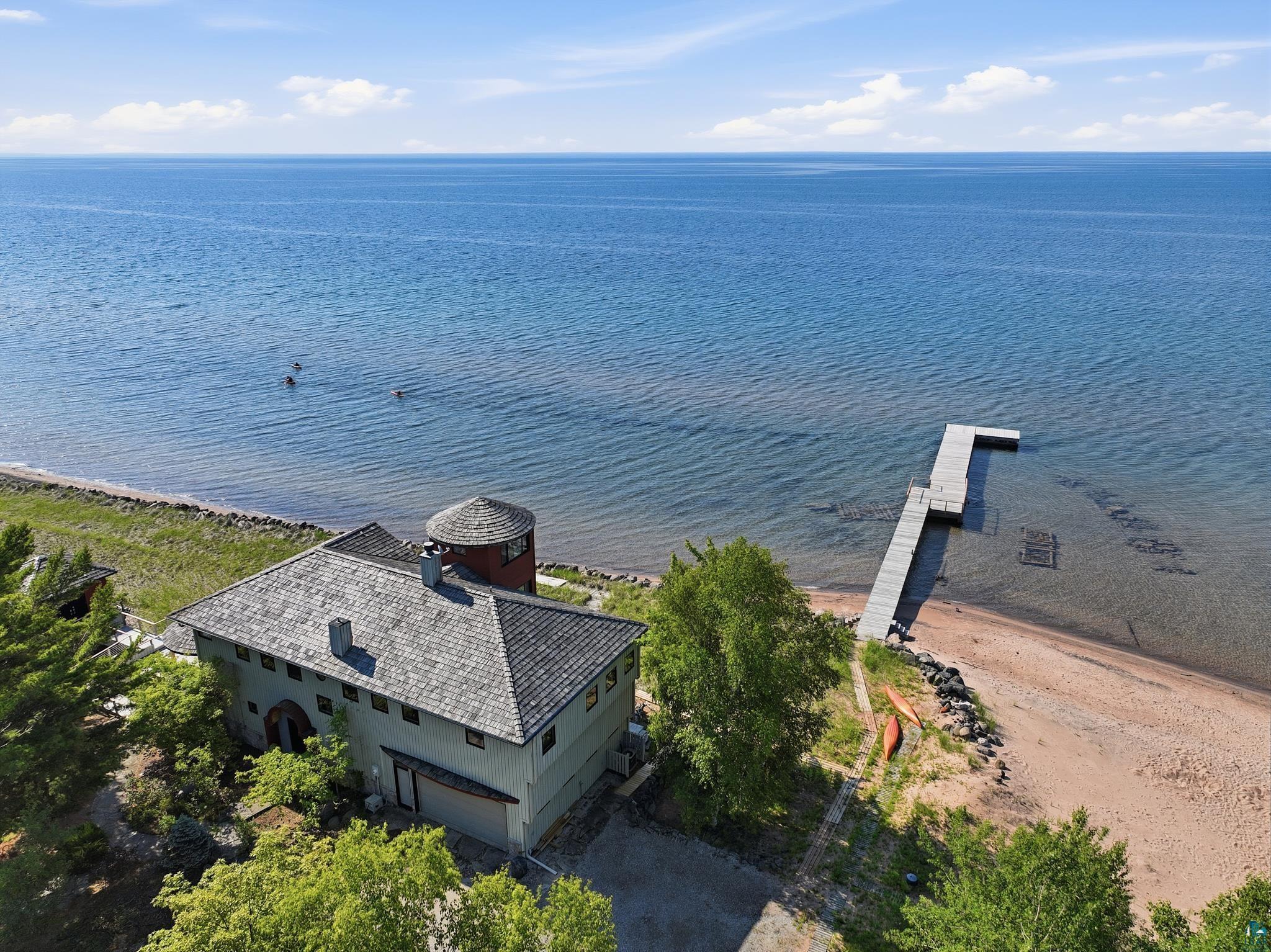 Image 3: Waterfront property featuring a private dock, sandy beach, and a stucco exterior with a distinctive turret, Aerial View