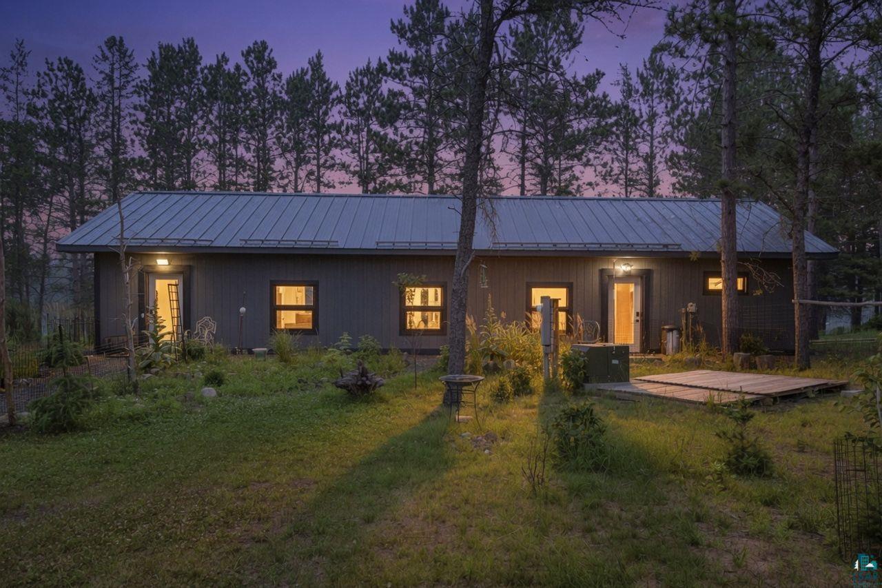 Image 0: Dark gray horizontal siding with a metal roof, Back Of Structure