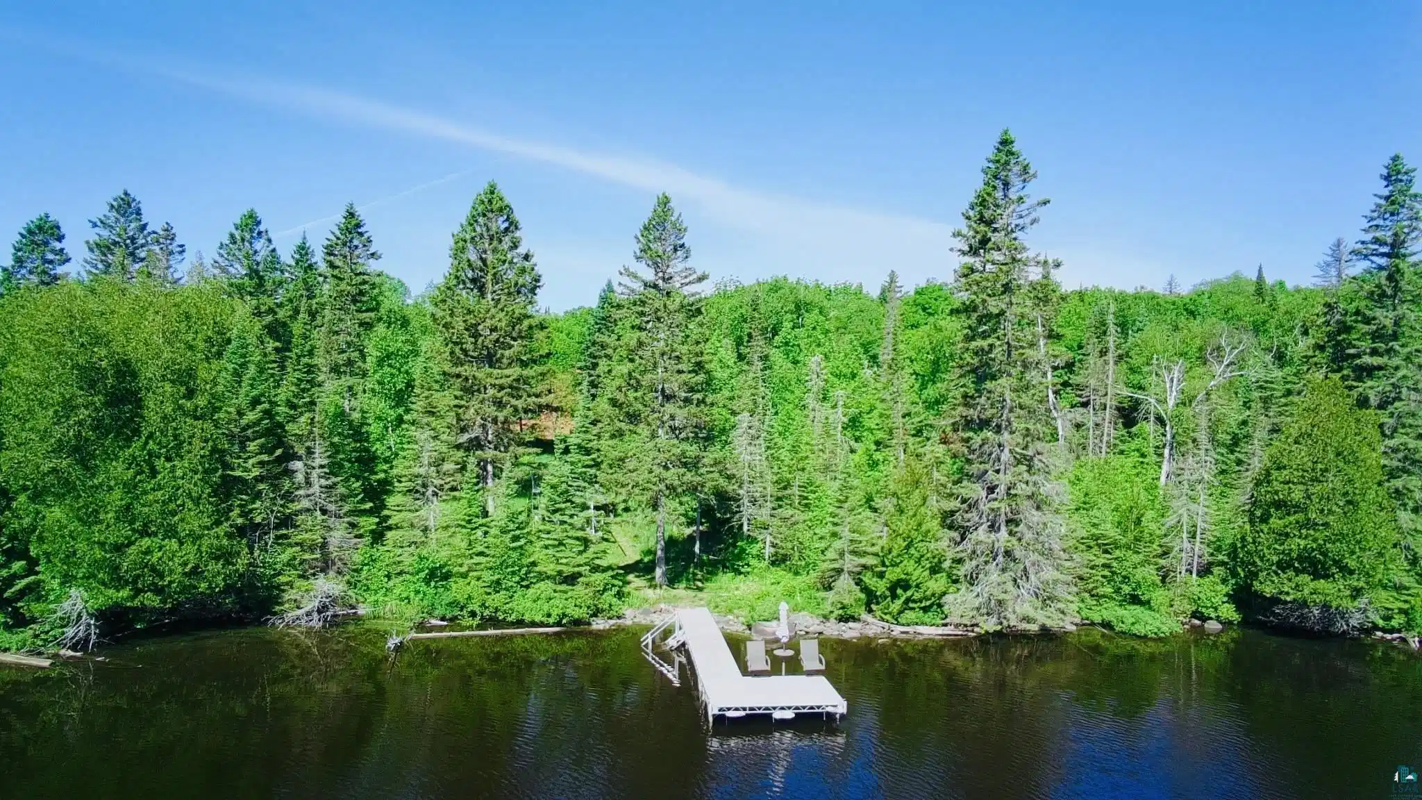 Image 0: Lakefront property featuring a private dock and a heavily wooded shoreline with mature trees, Caribou Lake Home