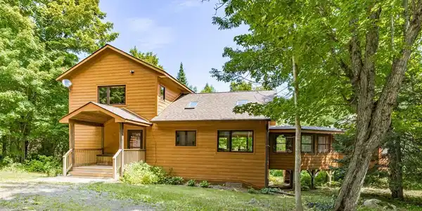 Image 3: Wood-sided exterior featuring multiple windows, a covered front porch, and an attached deck, Front Of Structure