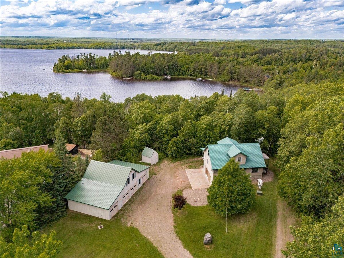 Image 3: Lakefront property featuring two structures with green metal roofs, surrounded by dense mature trees, Aerial View