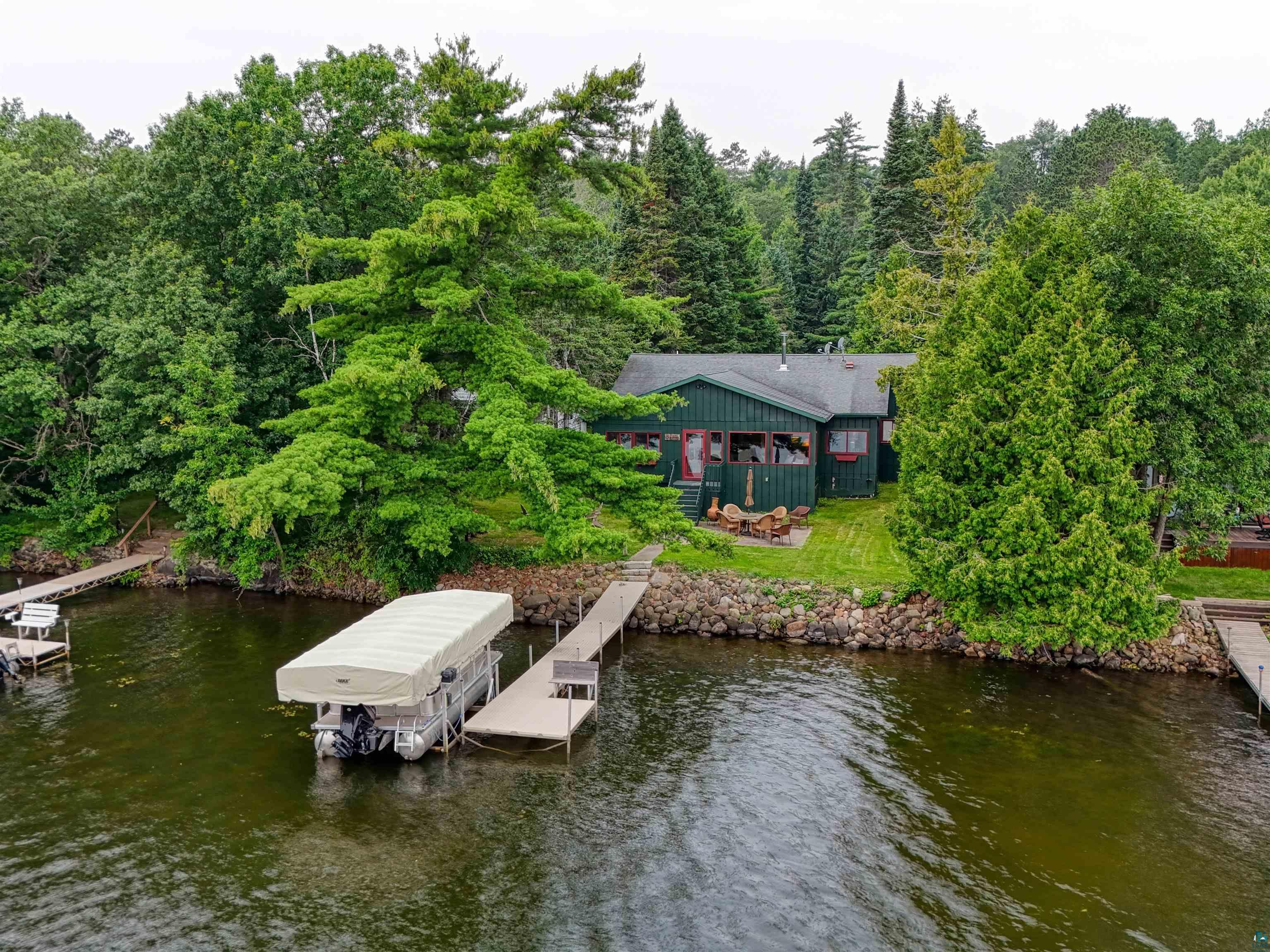 Image 0: Dock area featuring a water view, boat lift, and a forest view, Dock