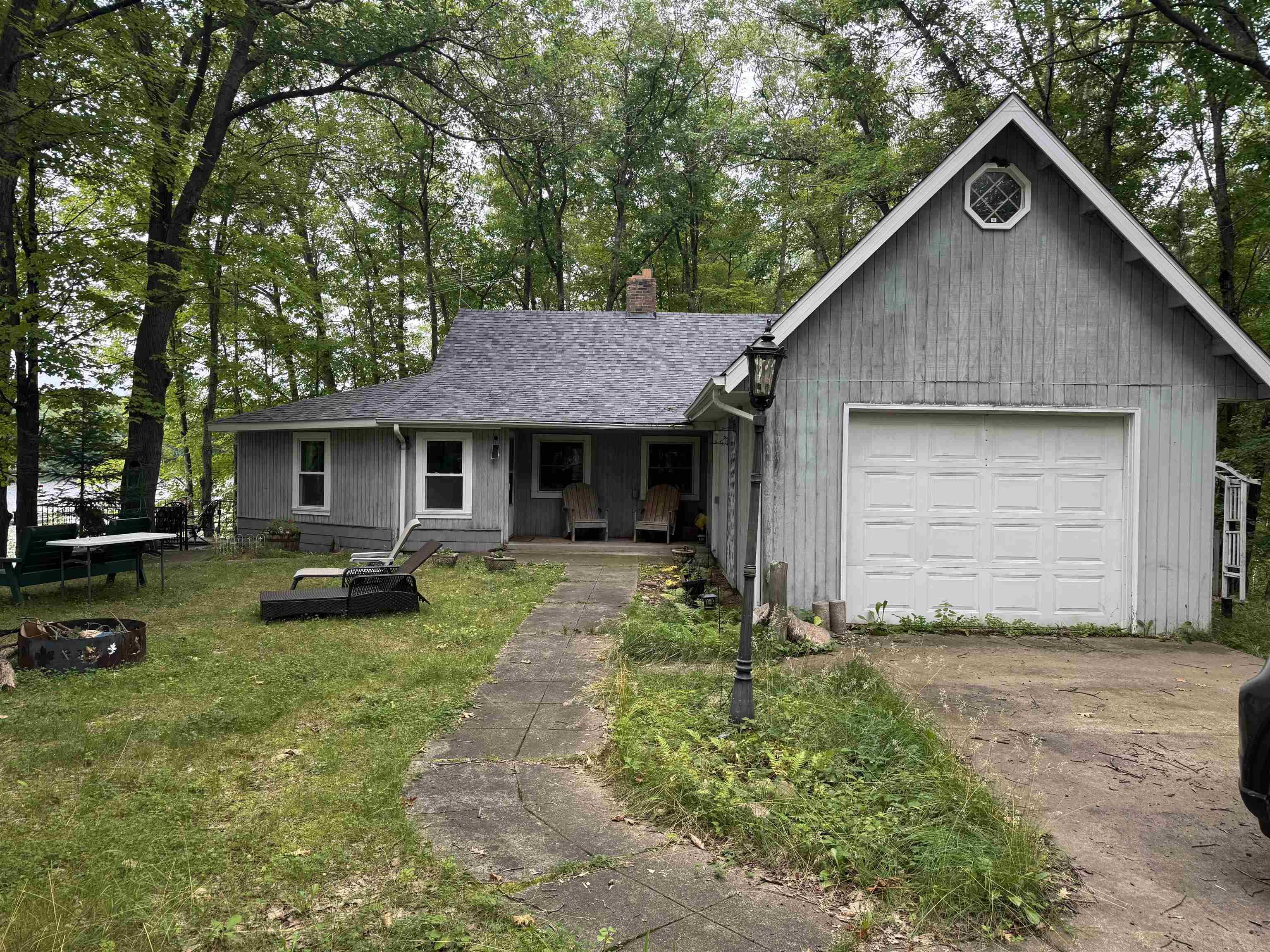 Image 2: View of front facade with covered porch, a garage, view of wooded area, and driveway, Front Of Structure
