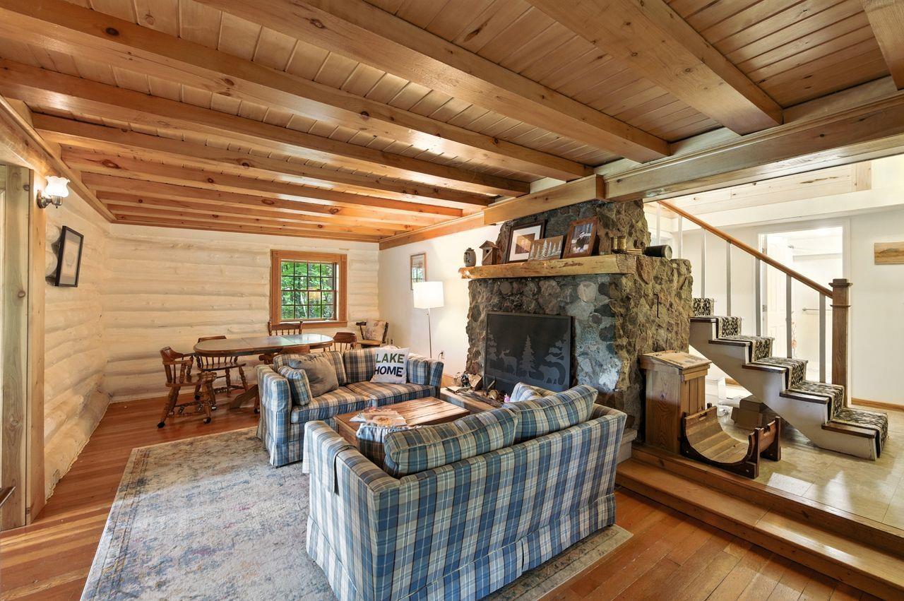 Image 4: Living area featuring hardwood / wood-style floors, a stone fireplace, and a wood ceiling with exposed beams, Living Room