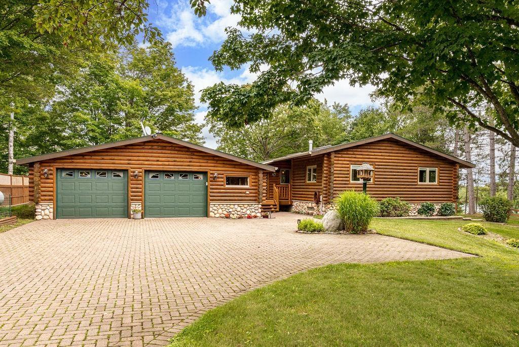Image 0: Log cabin with an attached garage, decorative driveway, a front lawn, and stone siding, Front Of Structure