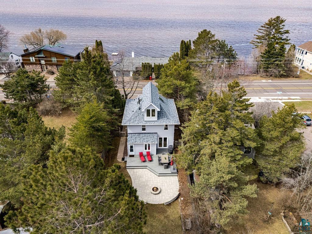 Image 1: Waterfront property featuring a multi-level new (2024) gray-shingled roof and light gray siding, Aerial View