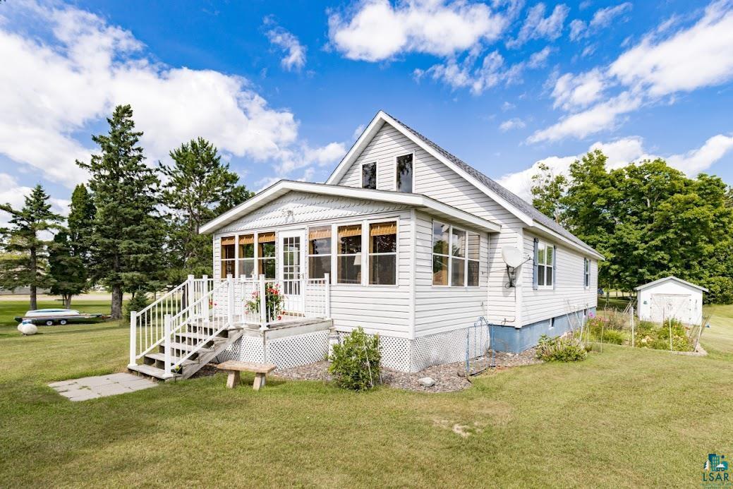 Image 1: White siding residence featuring a sunroom addition and an exterior stairway with white railings, Front Of Structure