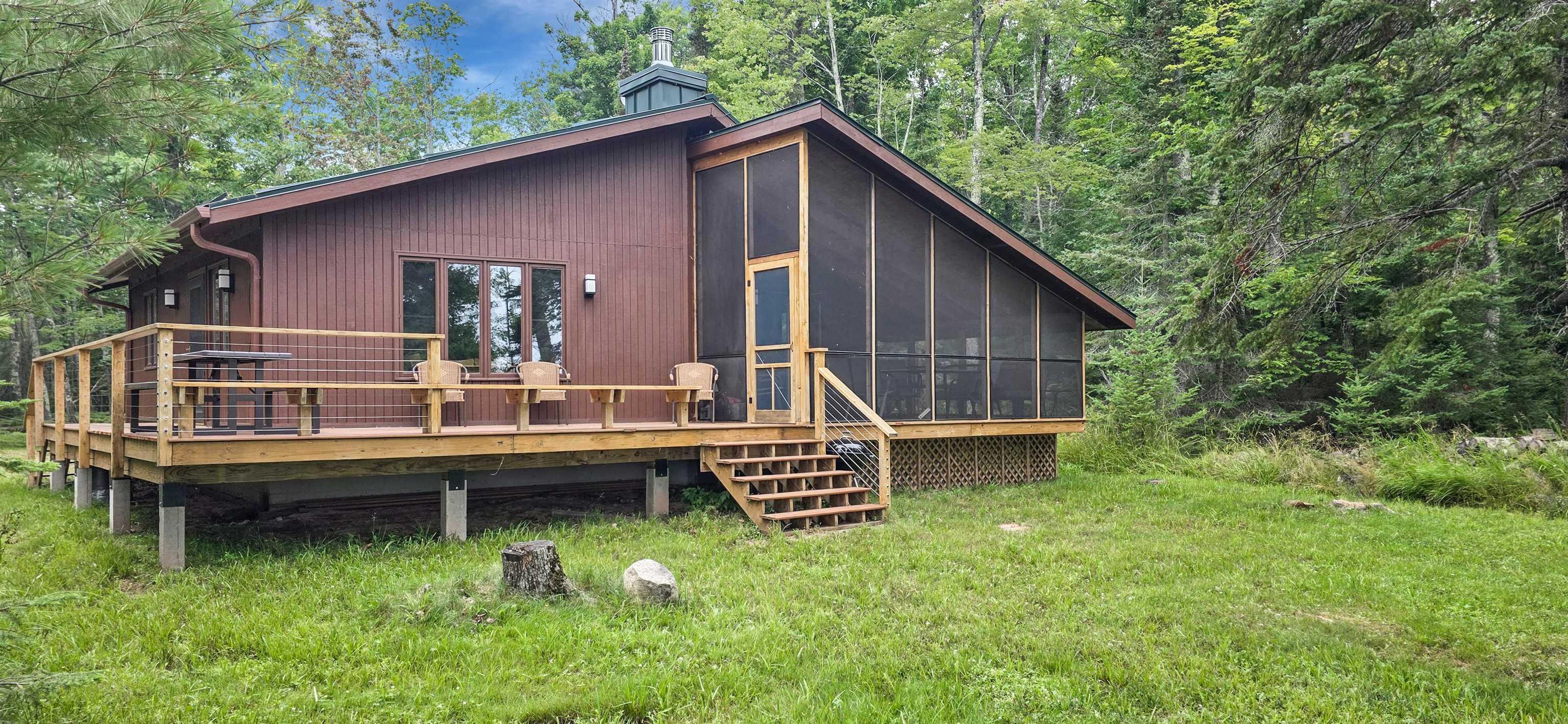 Image 0: Back of house featuring a sunroom, a wooden deck, a lawn, and a view of trees, Back Of Structure