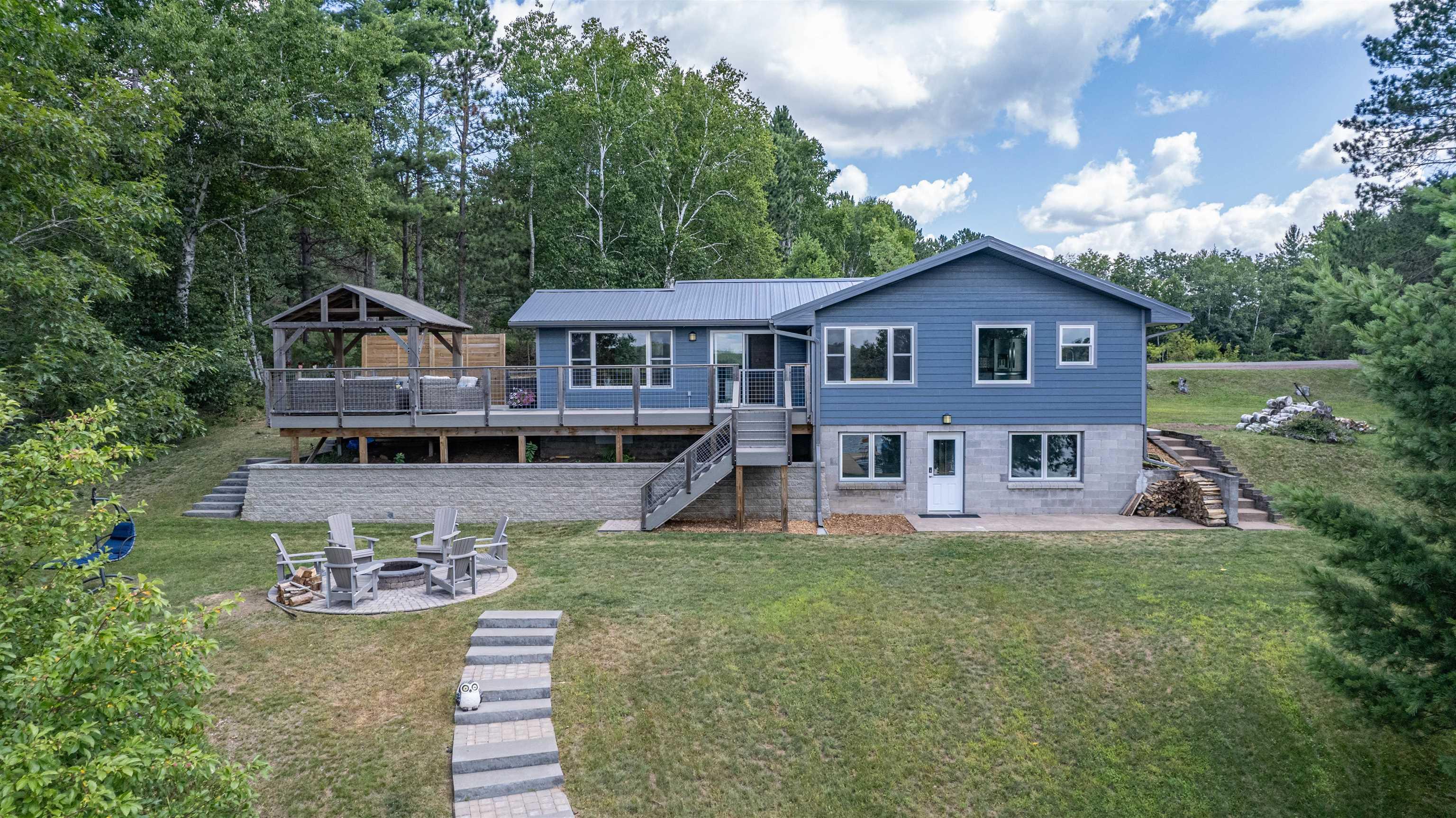 Image 1: Rear view of property with stairway, a patio area, an outdoor fire pit, and a yard, Back Of Structure