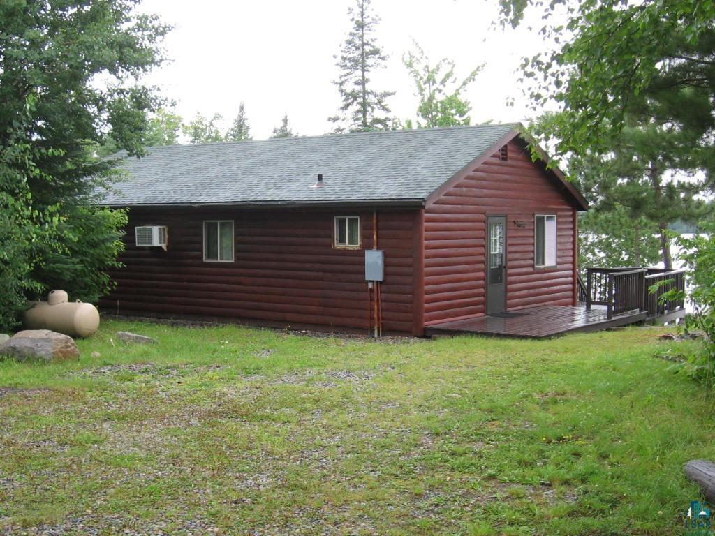 Image 1: View of home's exterior featuring faux log siding, a deck, a shingled roof, and a lawn, Side Of Structure