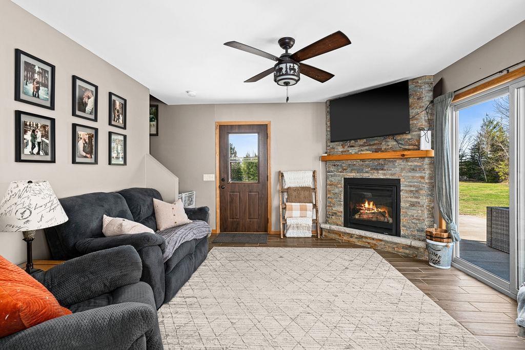 Image 1: Living area with wood finished floors, a ceiling fan, and a fireplace, Living Room
