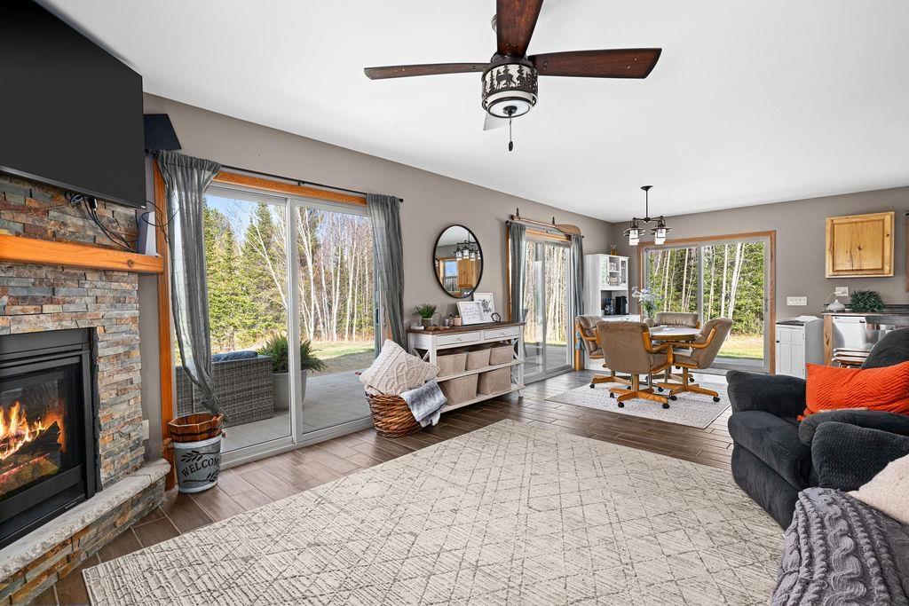 Image 2: Living room featuring wood-type flooring, healthy amount of natural light, ceiling fan, and a stone fireplace, Living Room