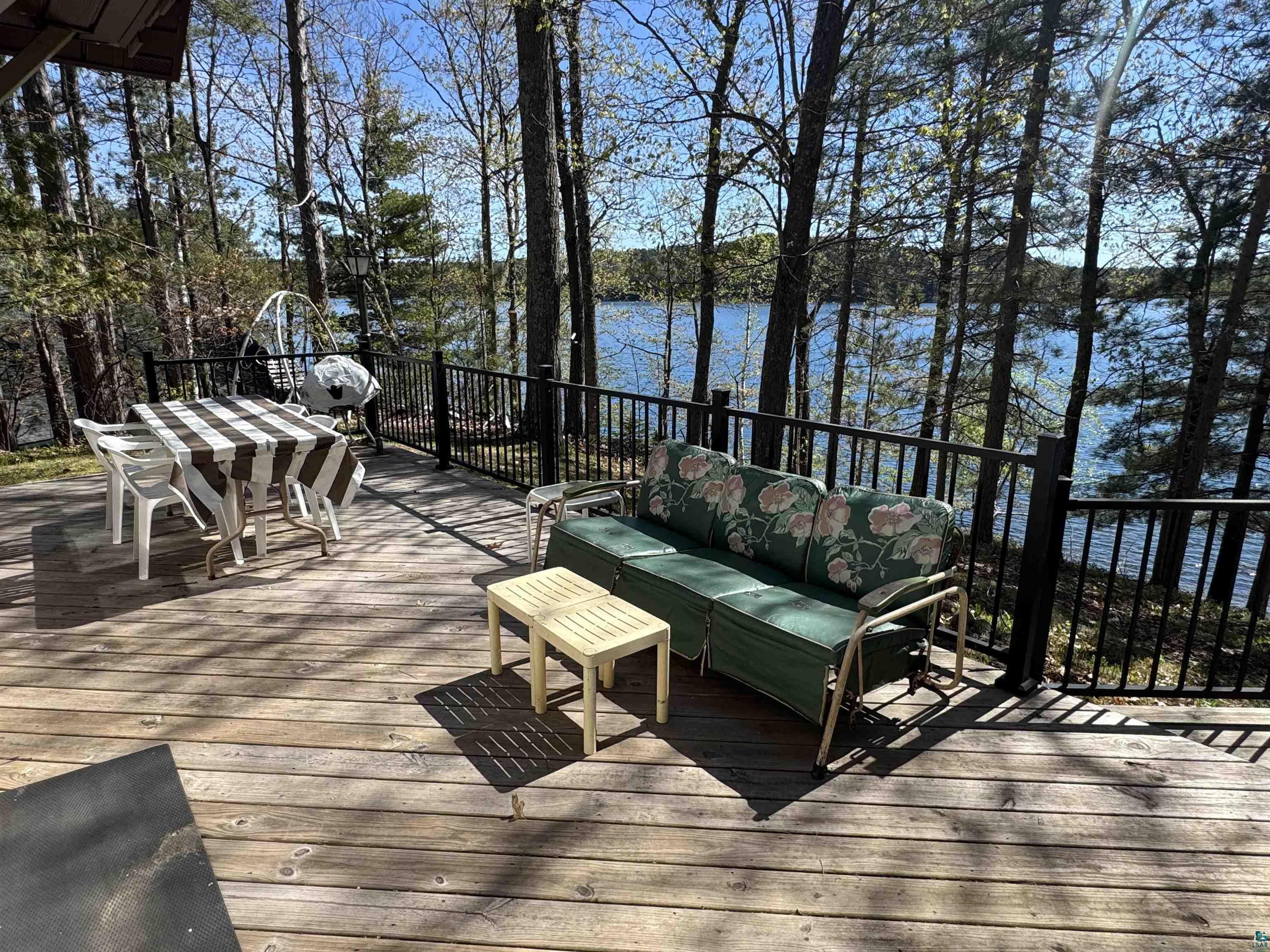 Image 4: Expansive wood deck with black metal railings, overlooking a lake with surrounding trees, Deck