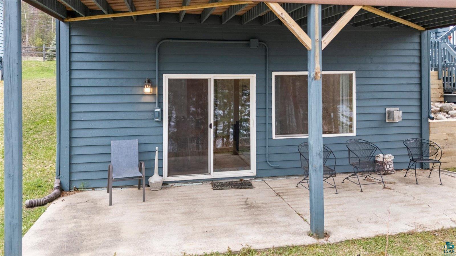 Image 2: Lower-level concrete patio featuring a sliding glass door entry, single window, exterior wall lighting, and horizontal siding, Entry