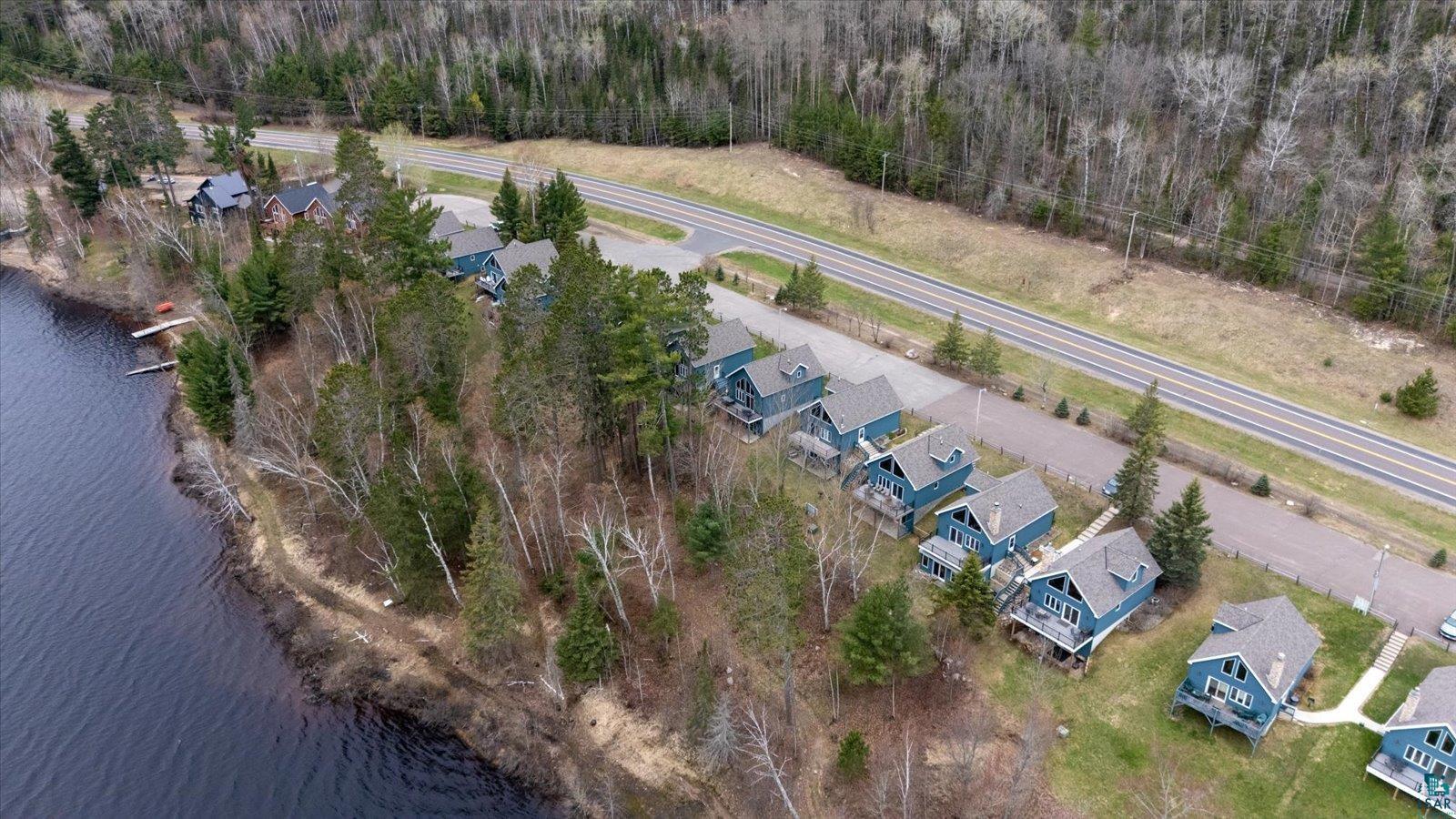 Image 3: Waterfront properties featuring a natural shoreline, mature trees, individual docks, and a paved access road, Aerial View