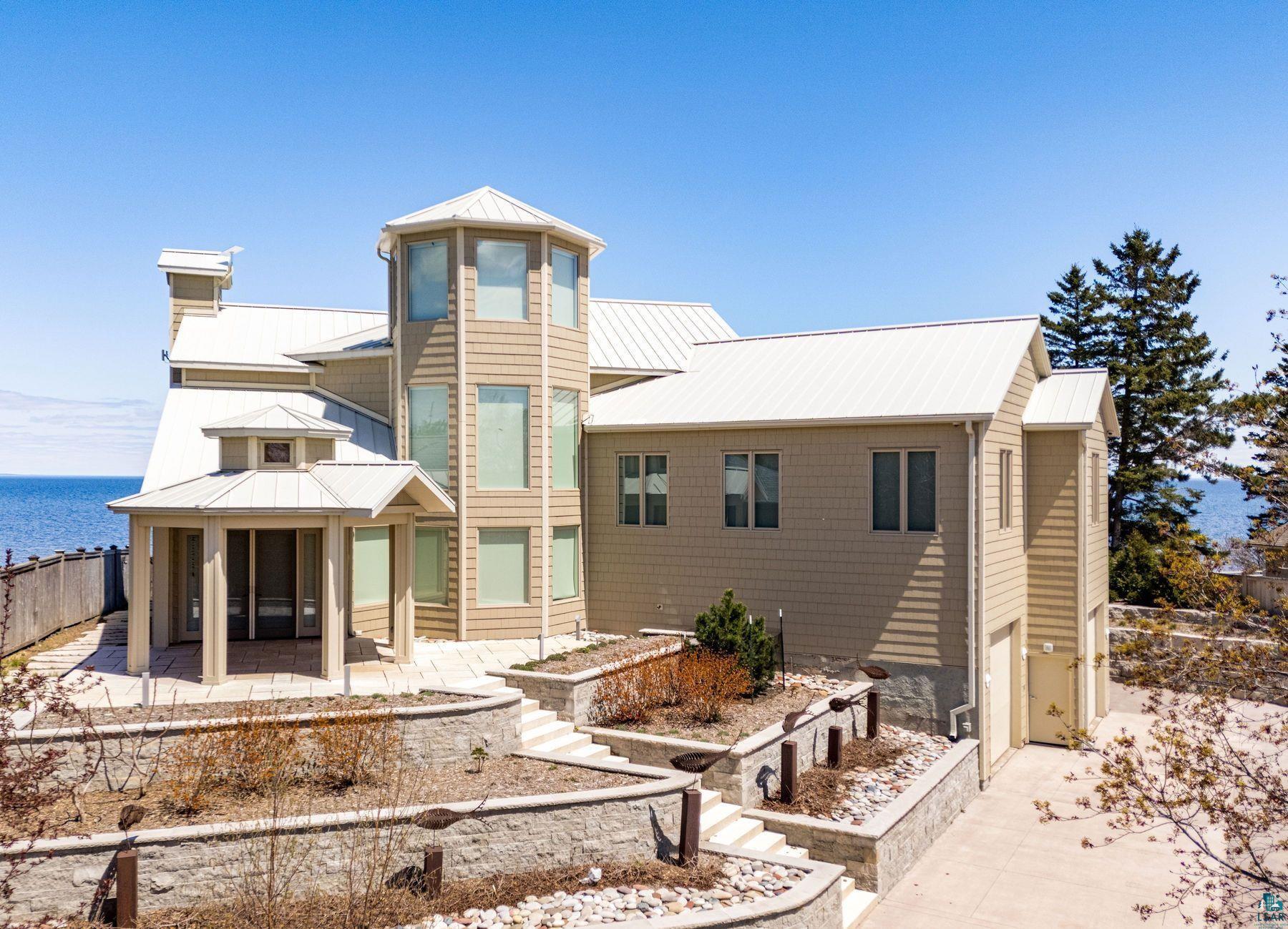 Image 3: Contemporary multi-level residence featuring a prominent octagonal tower, extensive window placements, and a light-colored metal roof, Back Of Structure