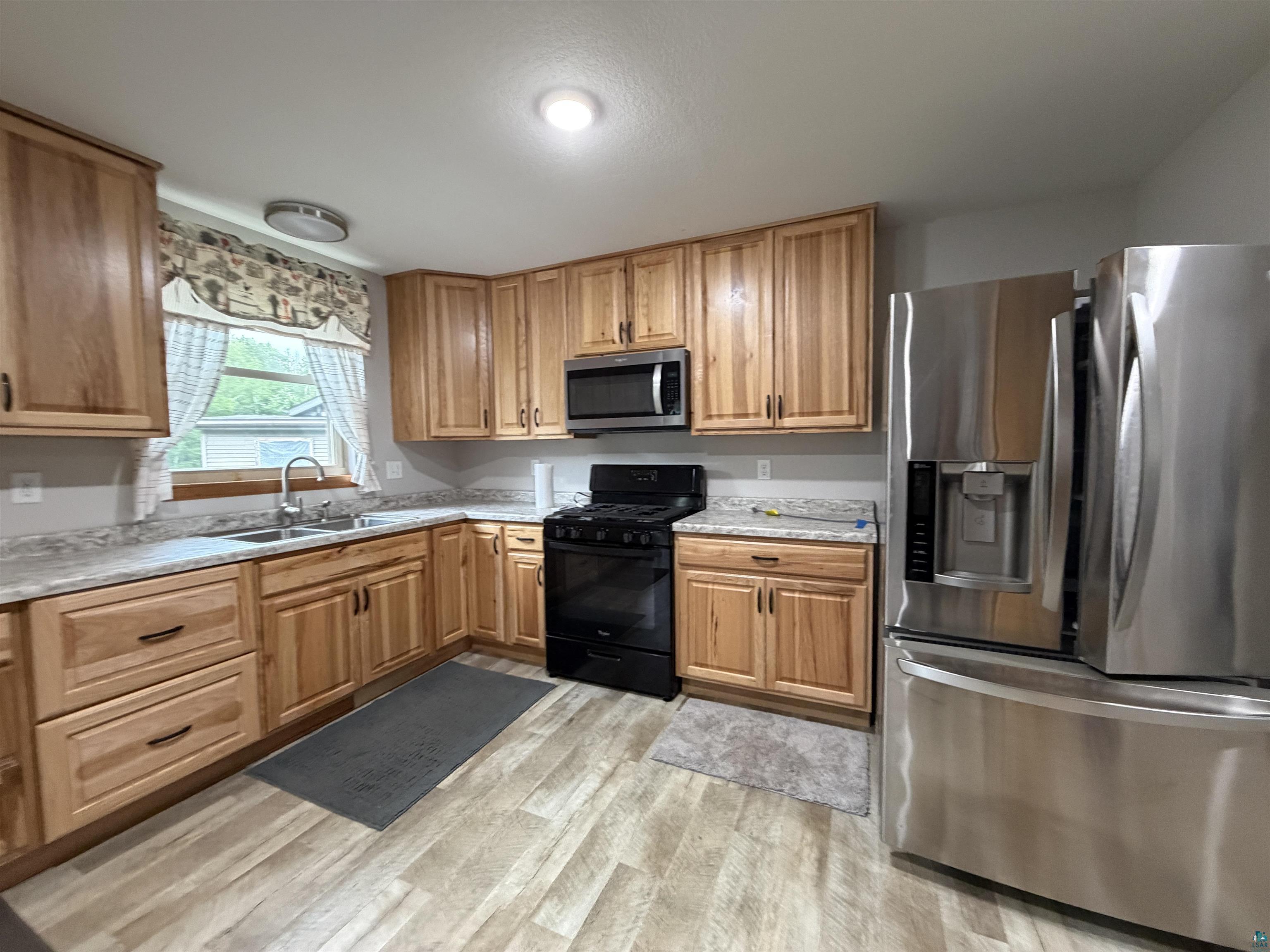 Image 3: Kitchen featuring light-tone wood cabinetry with dark hardware, stainless steel appliances, and wood-finish flooring, Kitchen