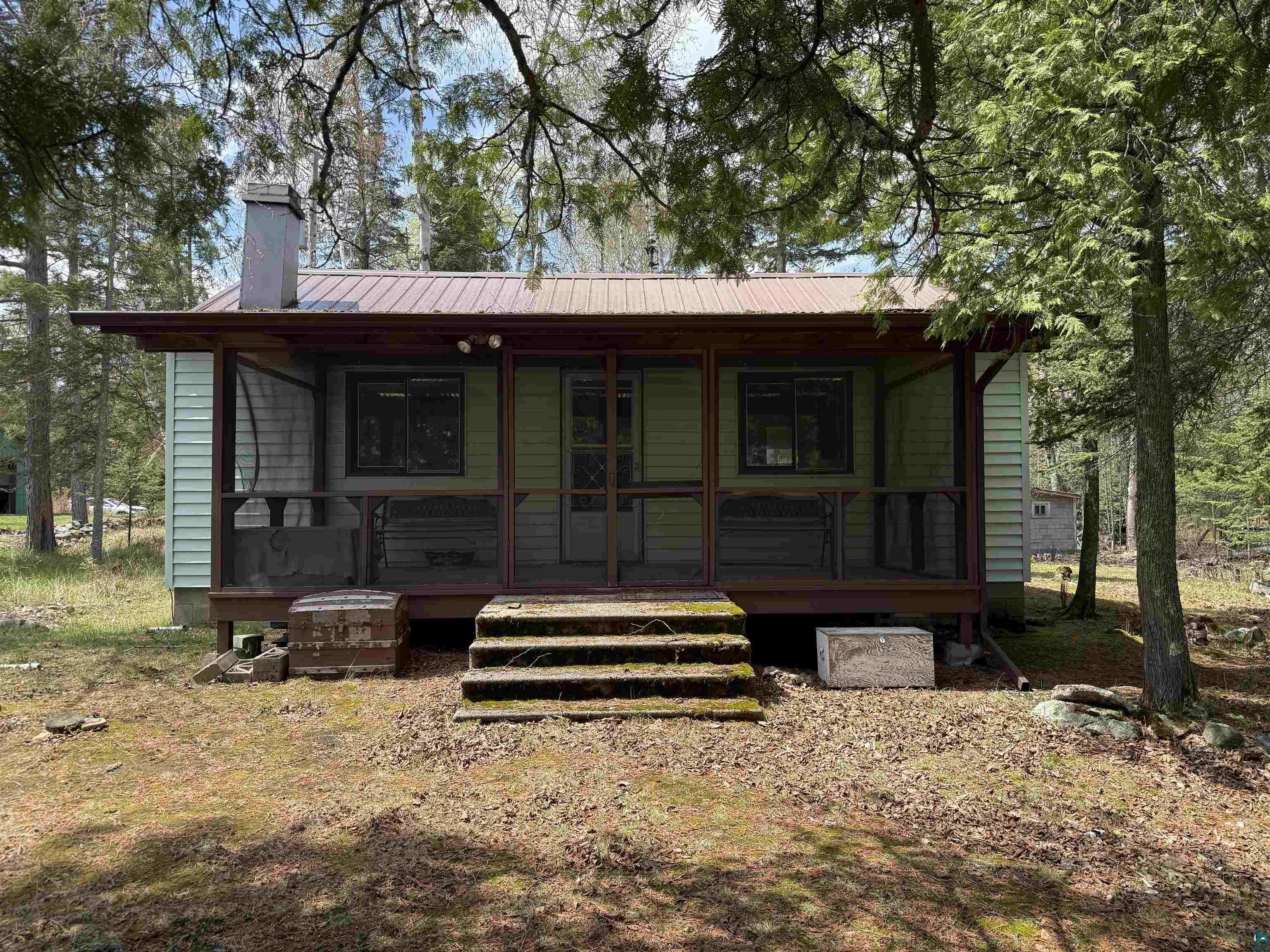 Image 0: Exterior featuring light green horizontal vinyl siding and a brown metal roof. Screen porch with a view of the lake., Lake side.