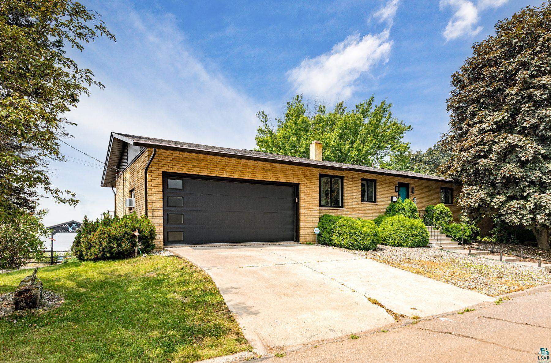 Image 1: Brick exterior featuring a dark gray garage door with frosted window panels, Front Of Structure