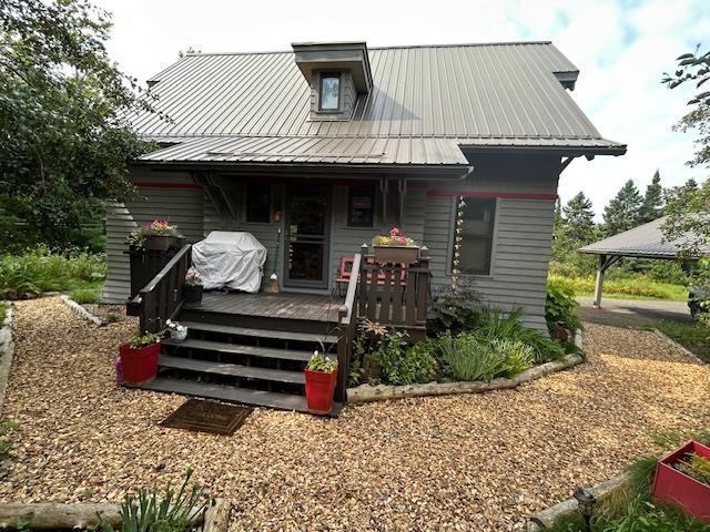 Image 1: Rear view of property featuring a metal roof and a wooden deck