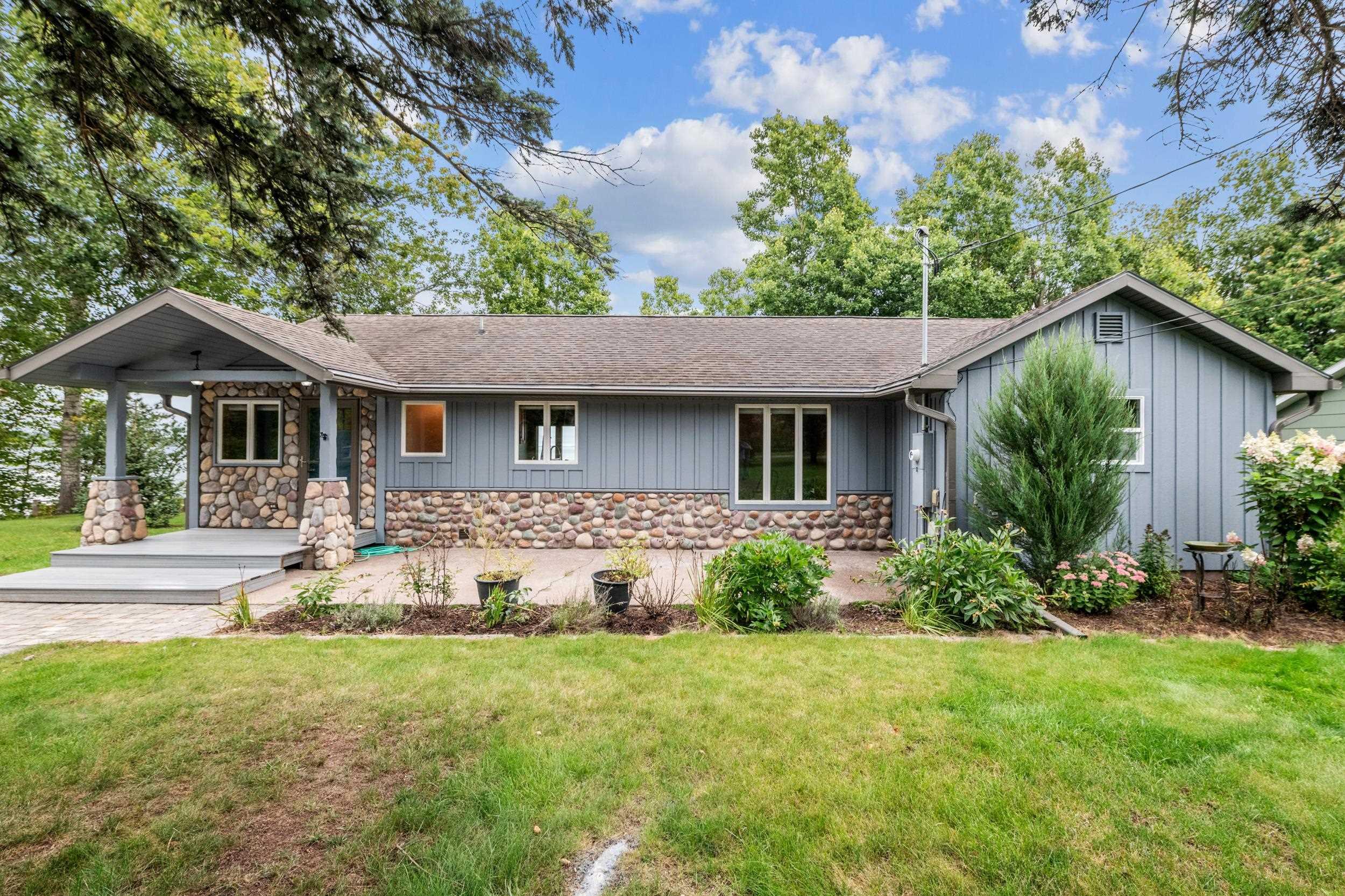 Image 2: Ranch-style home with stone siding, a front lawn, a shingled roof, and a patio, Front Of Structure