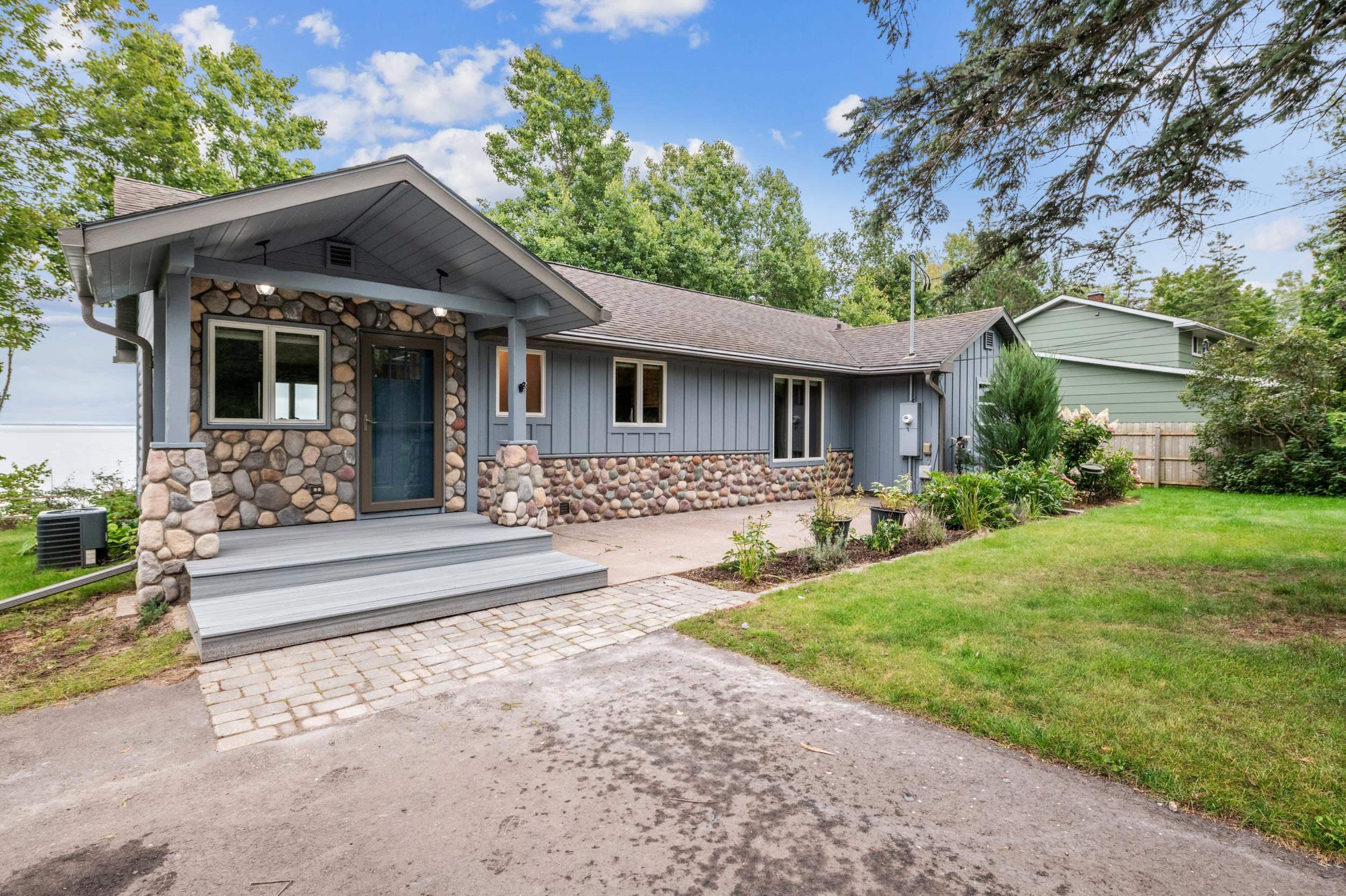 Image 3: View of front of home with stone siding, board and batten siding, and a shingled roof, Front Of Structure