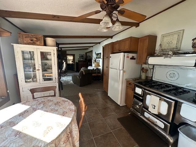 Image 2: Kitchen with brown cabinets, beamed ceiling, freestanding refrigerator, exhaust hood, and a textured ceiling, Kitchen