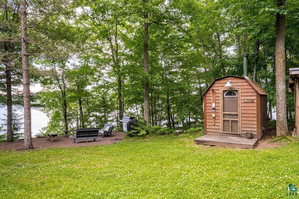 Image 2: Wood-sided outbuilding with a curved roofline and front porch, Yard