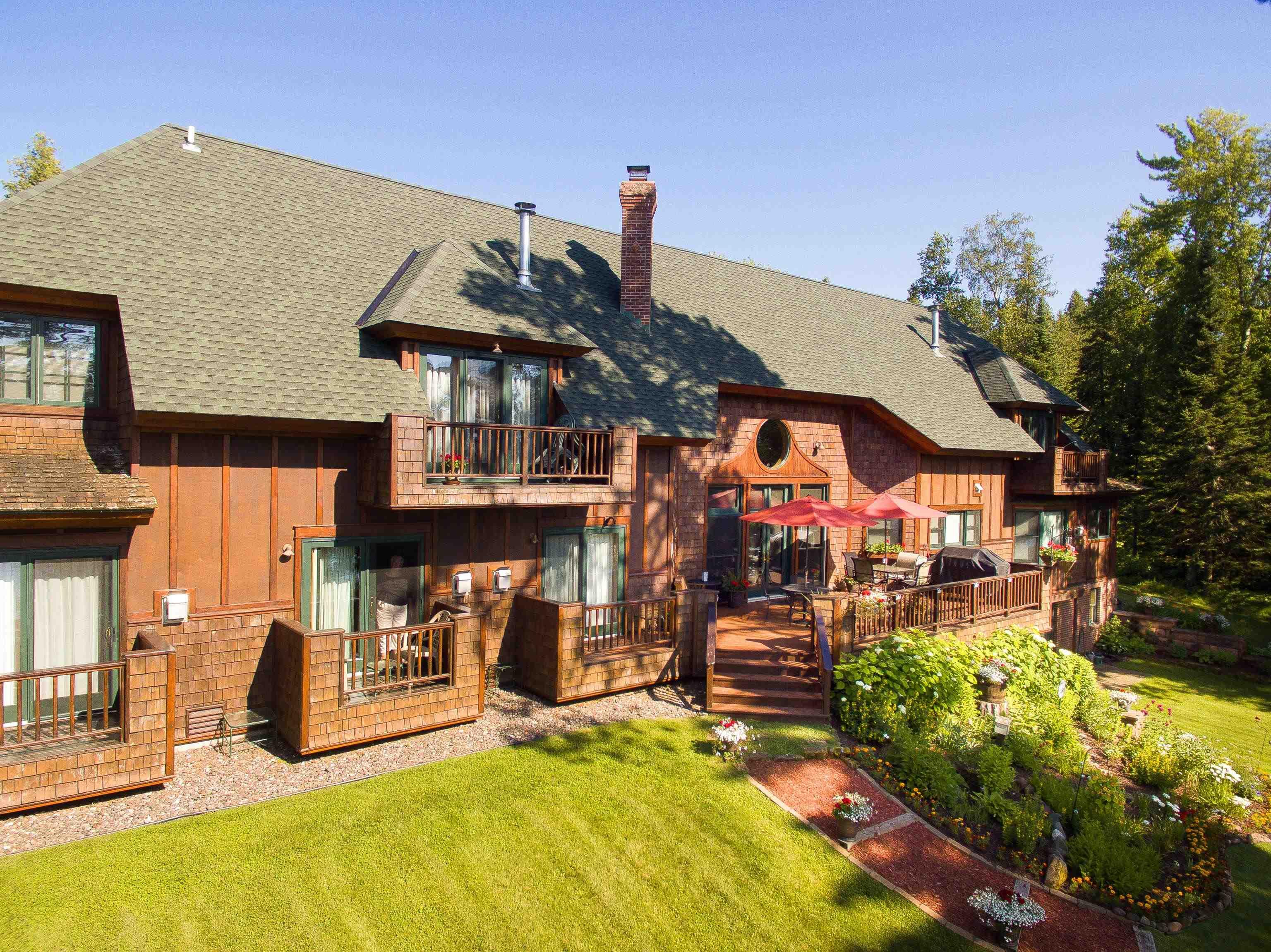 Image 1: Rear view of house with board and batten siding, a balcony, roof with shingles, a chimney, and a yard, Back Of Structure