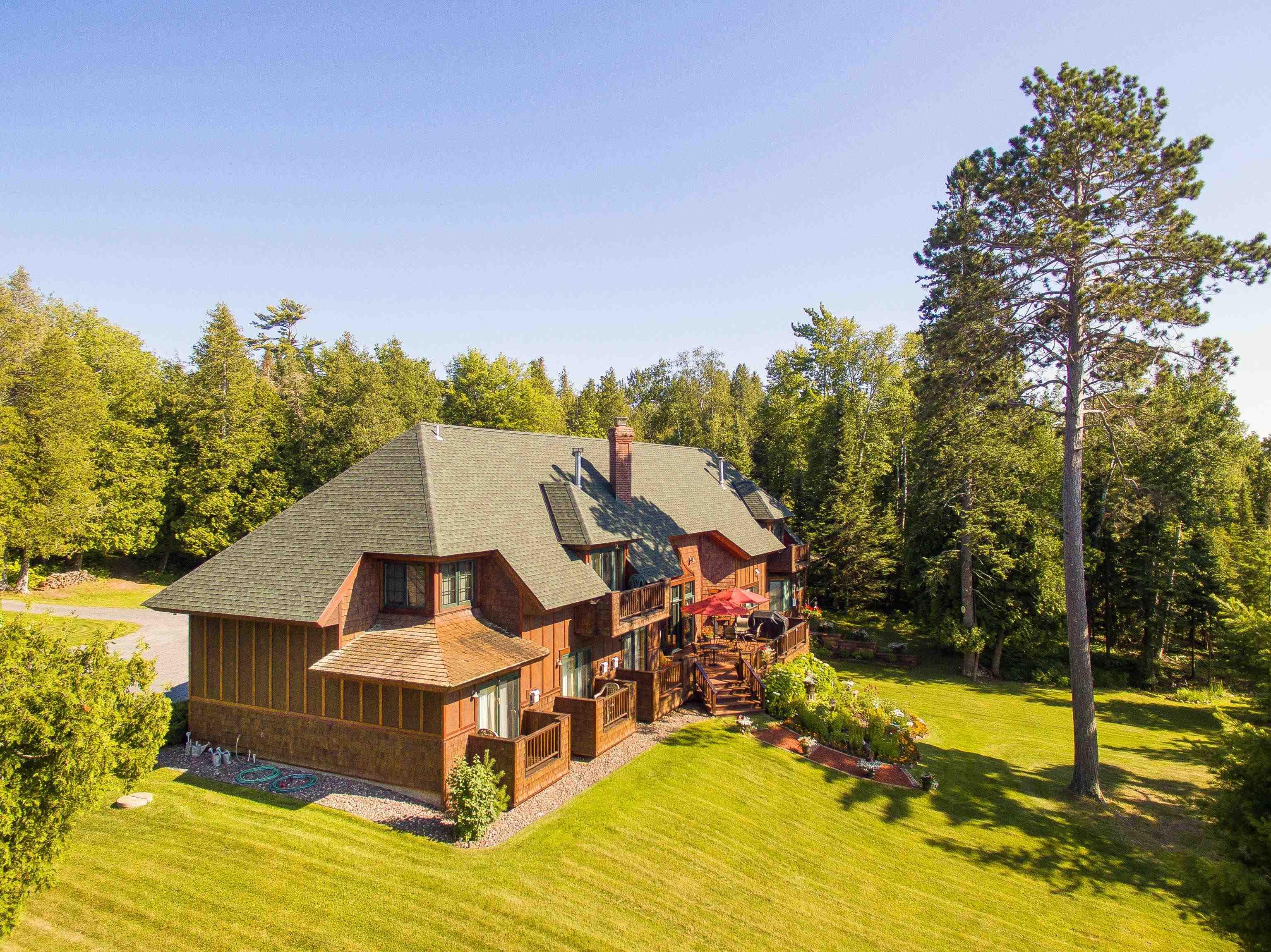 Image 3: Rear view of property with a shingled roof, a lawn, a wooden deck, a chimney, and a wooded view, Back Of Structure