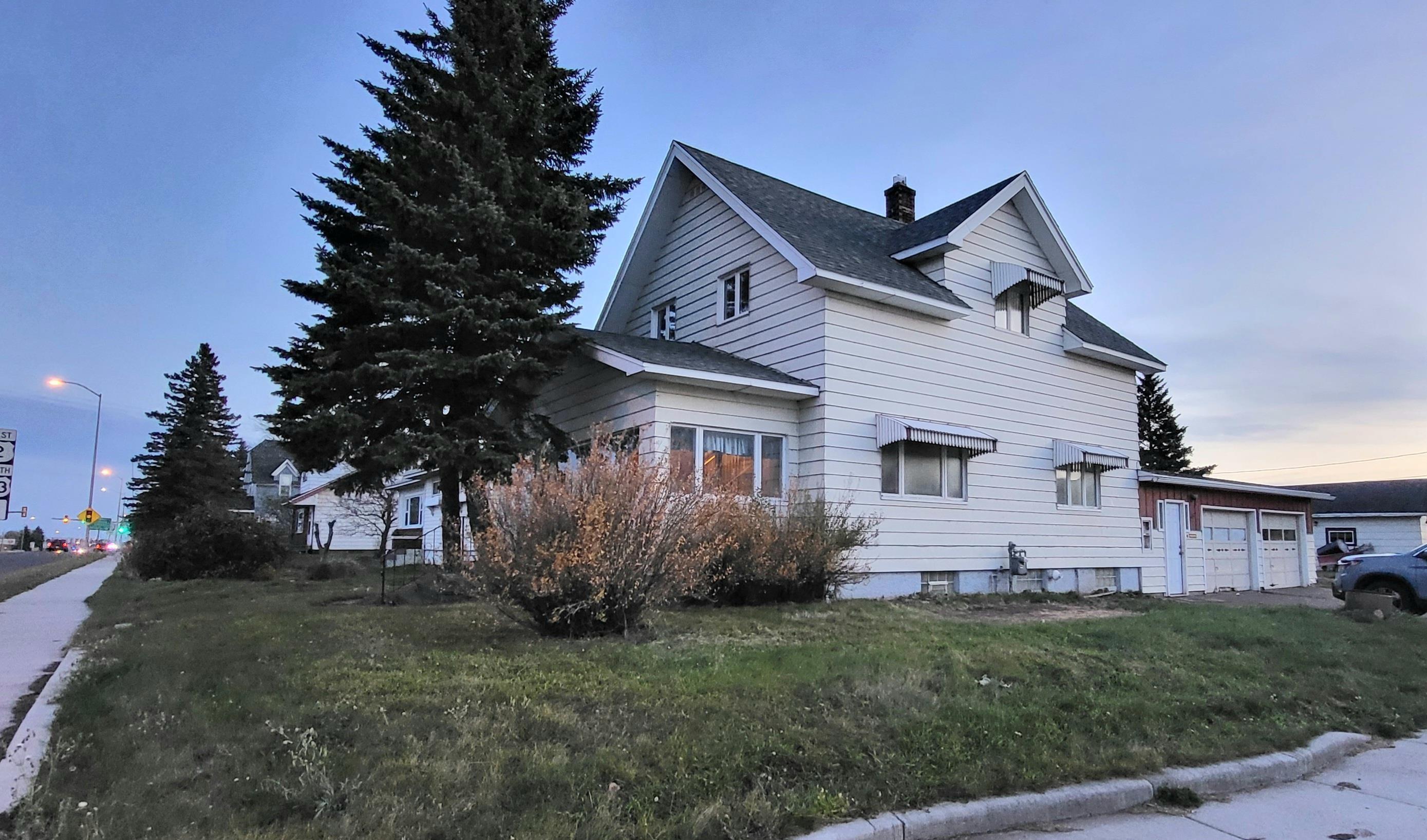 Image 0: View of side of home featuring a garage, a shingled roof, a chimney, and a lawn, Side Of Structure